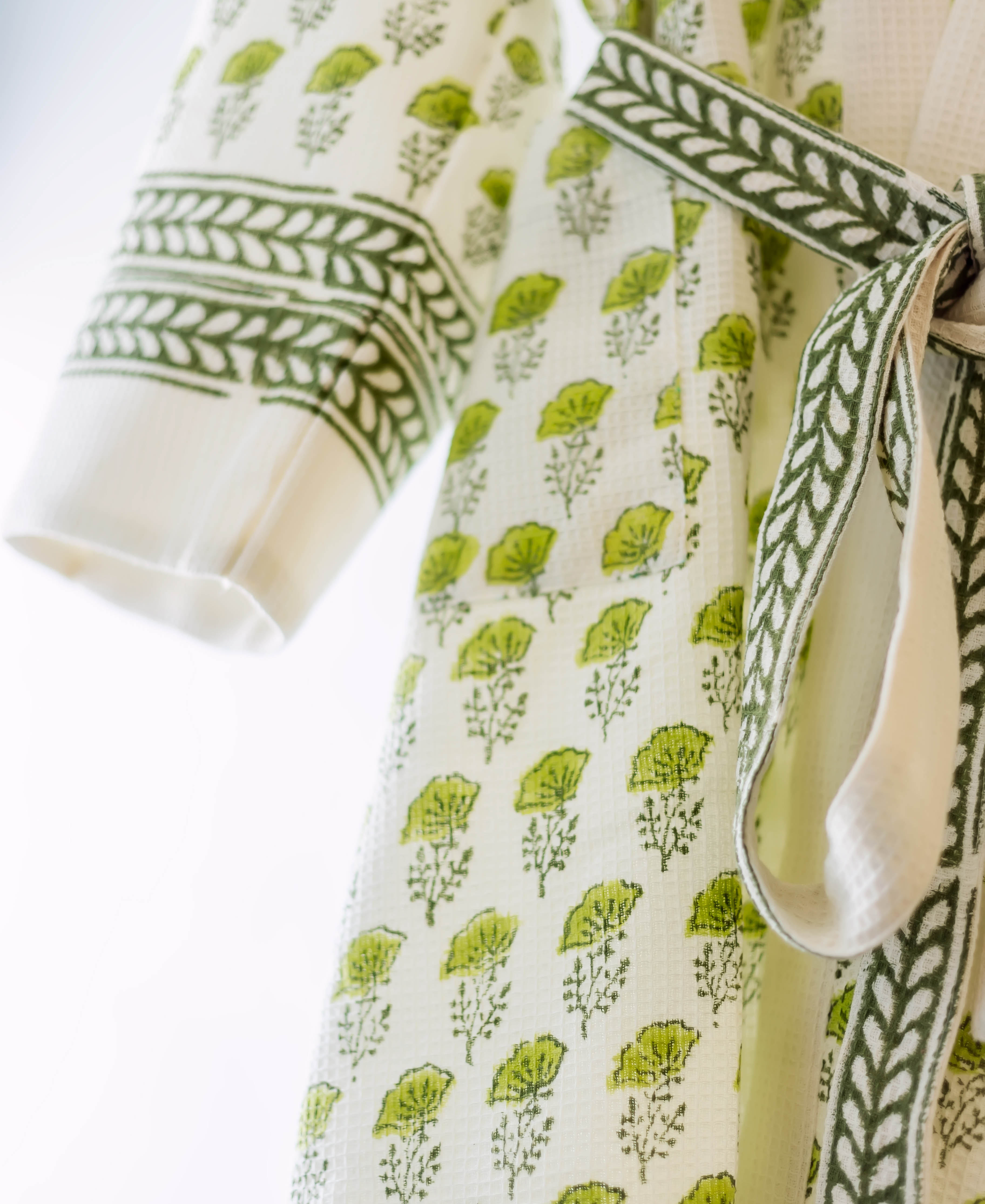 A close-up of a white and green hand-block-printed bath robe with a leafy pattern.