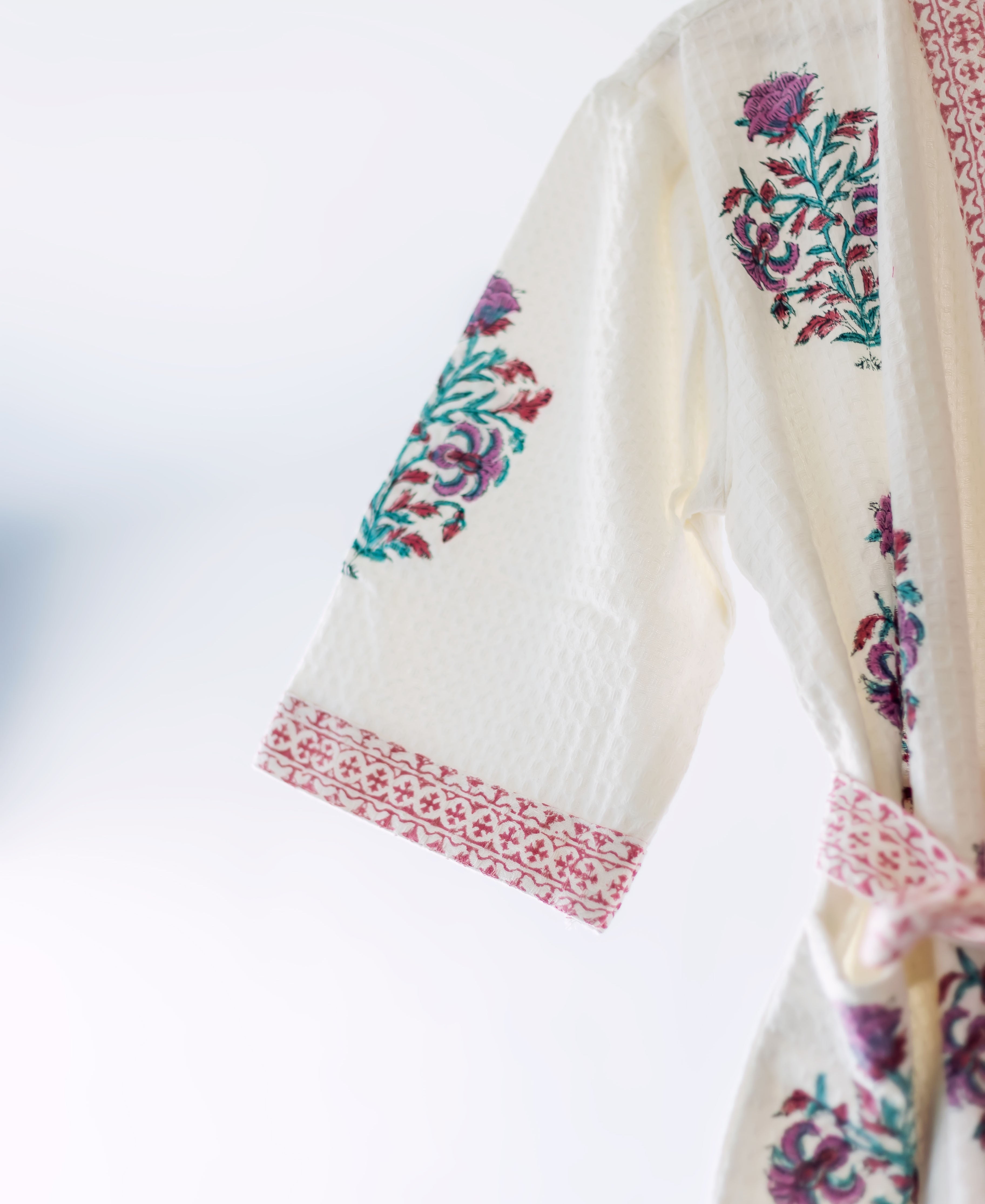 Close-up of cream hand-block printed robe sleeve with purple, teal floral and pink cuff.