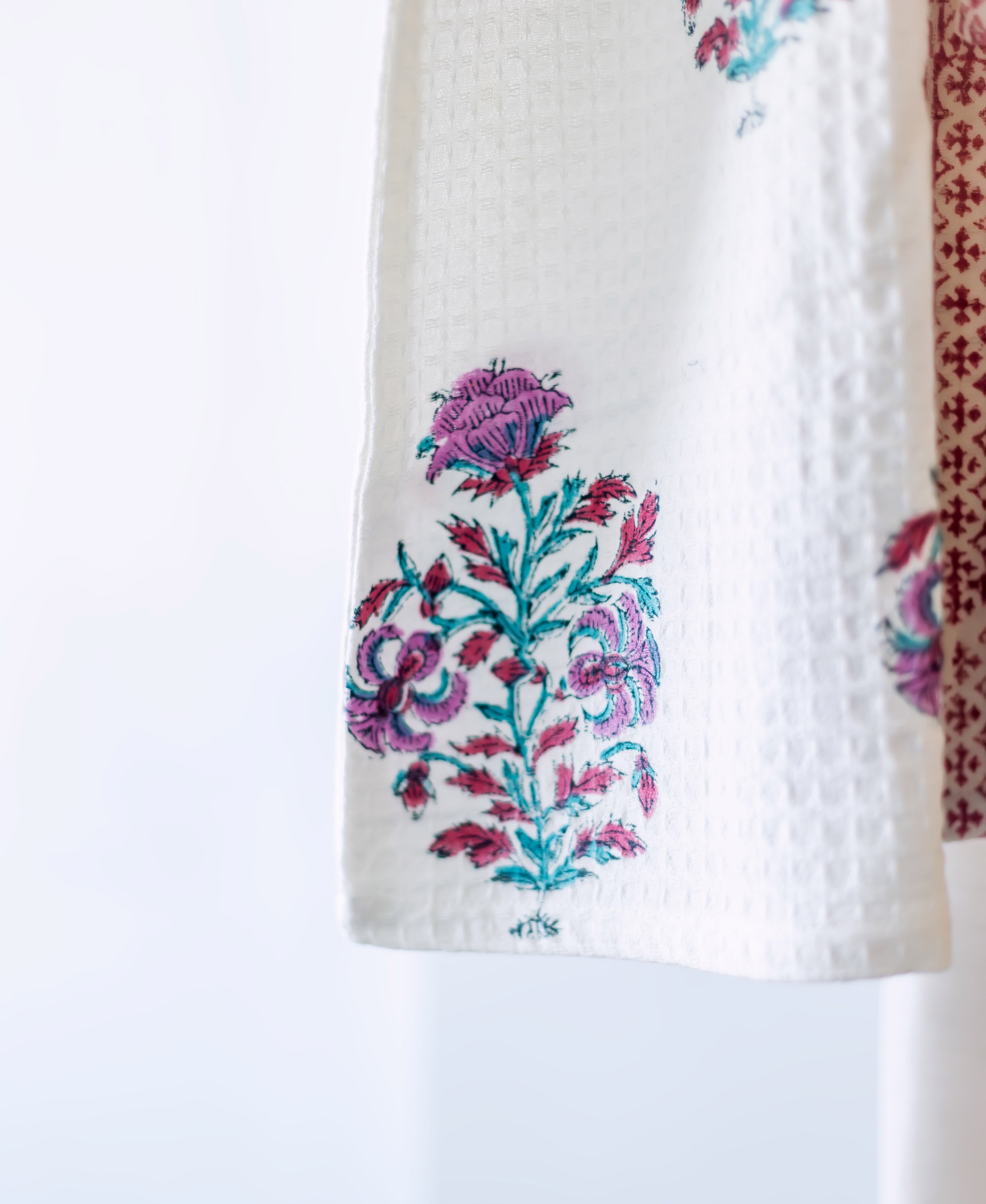 Close-up of white waffle robe with hand-block floral print in vibrant magenta and teal.