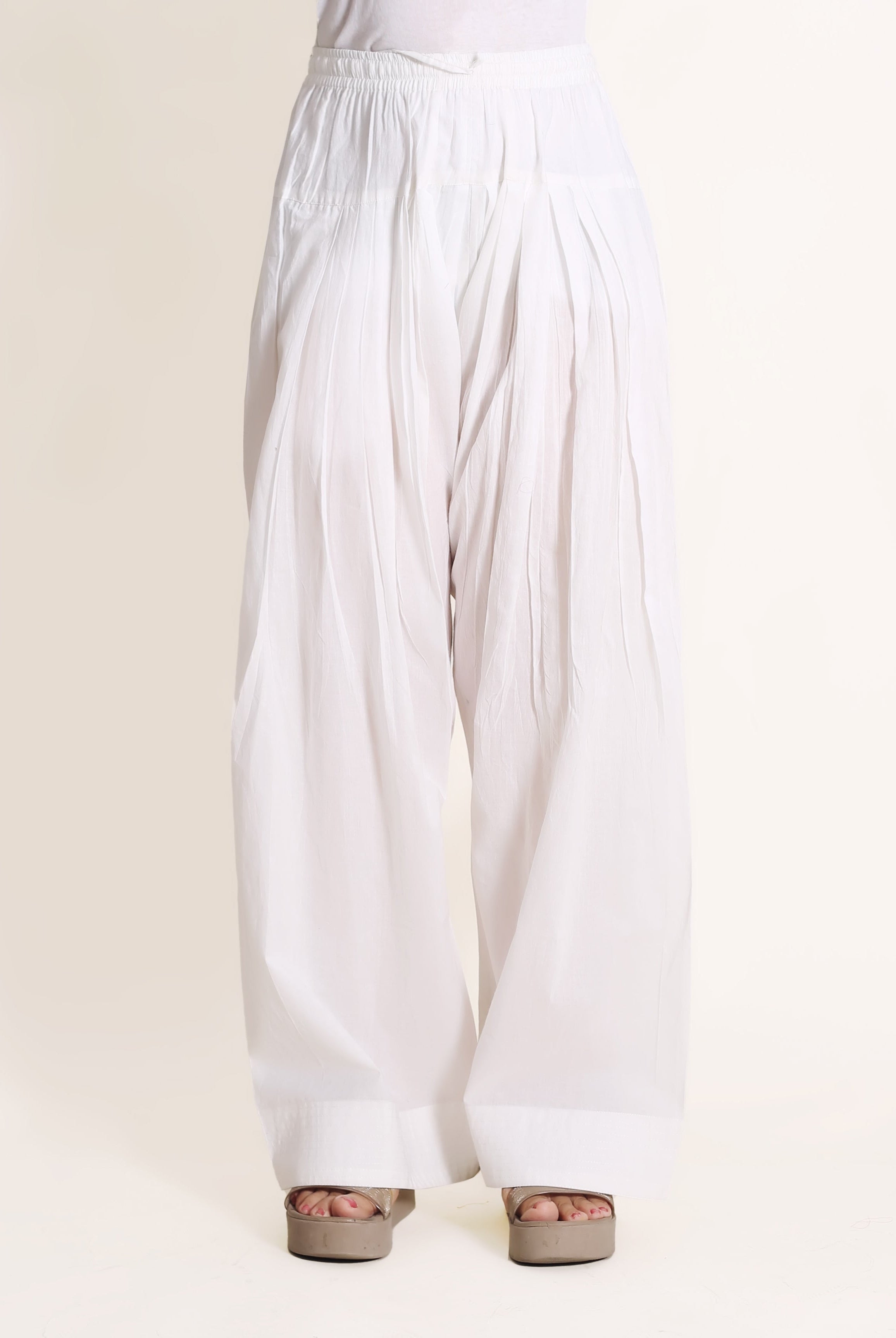 Solid white wide-legged pants with cuffed hem, on a model with sandals.