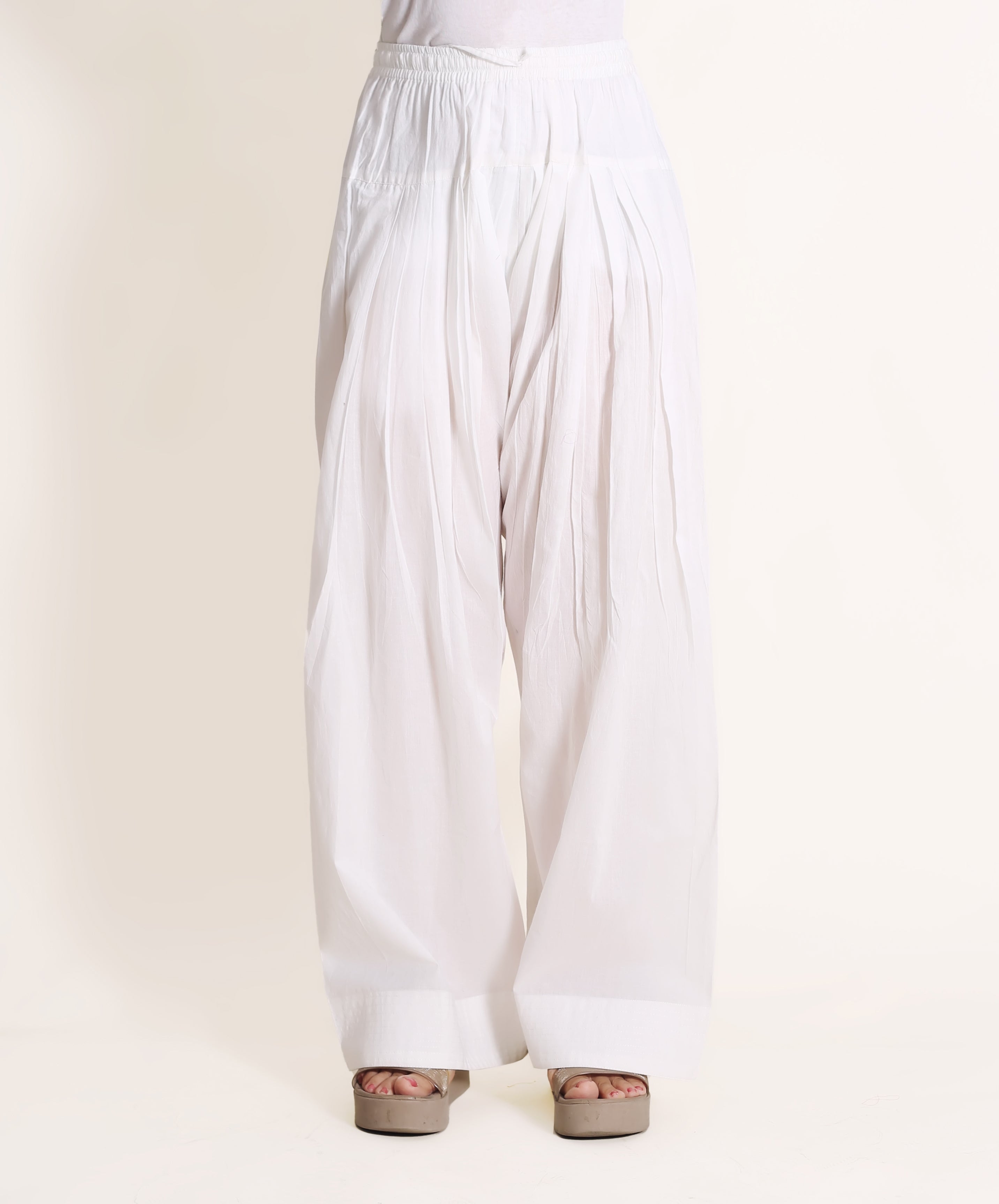 Solid white wide-legged pants with cuffed hem, on a model with sandals.