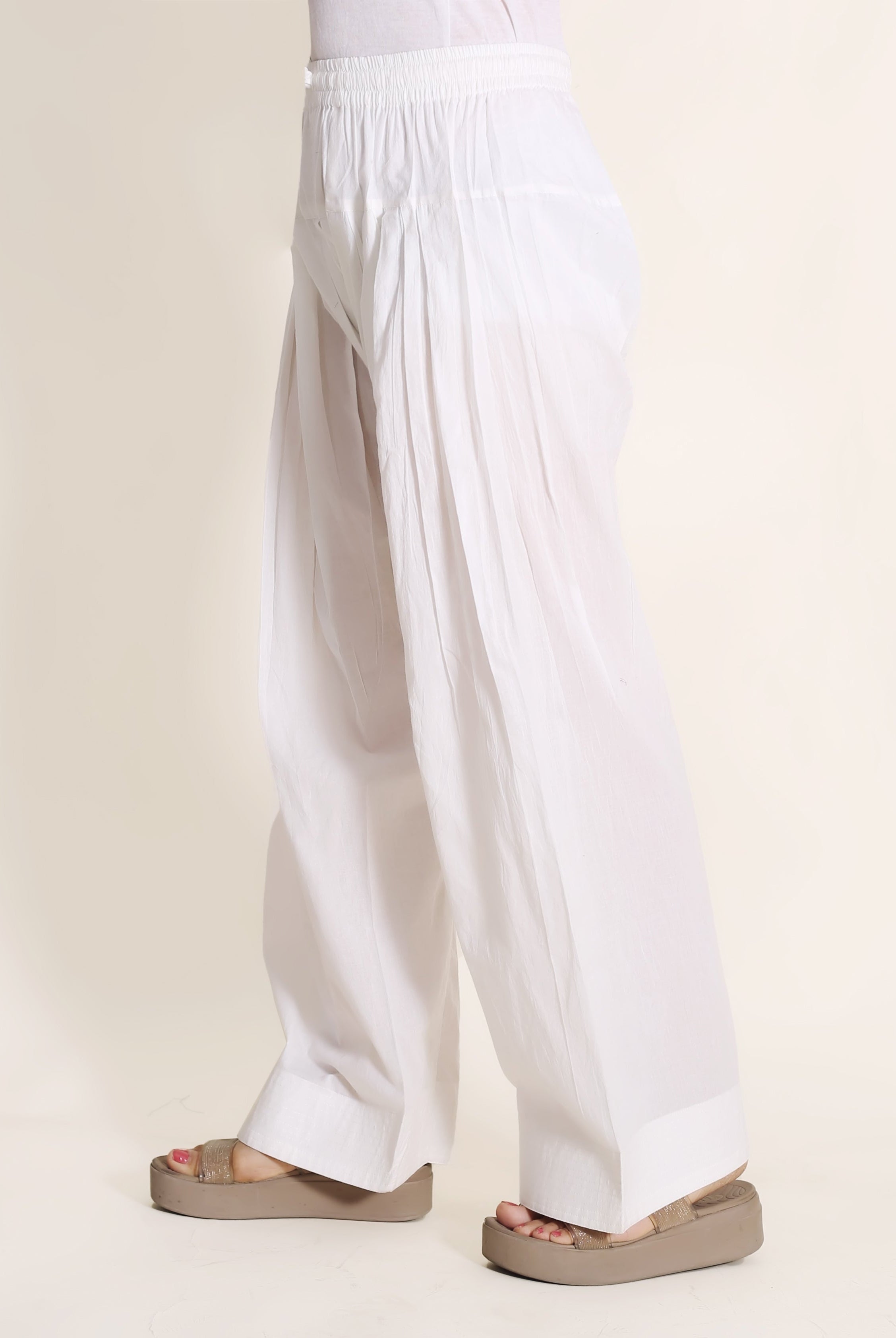 Side view of model wearing a comfortable, solid white pleated Farshi Salwar.