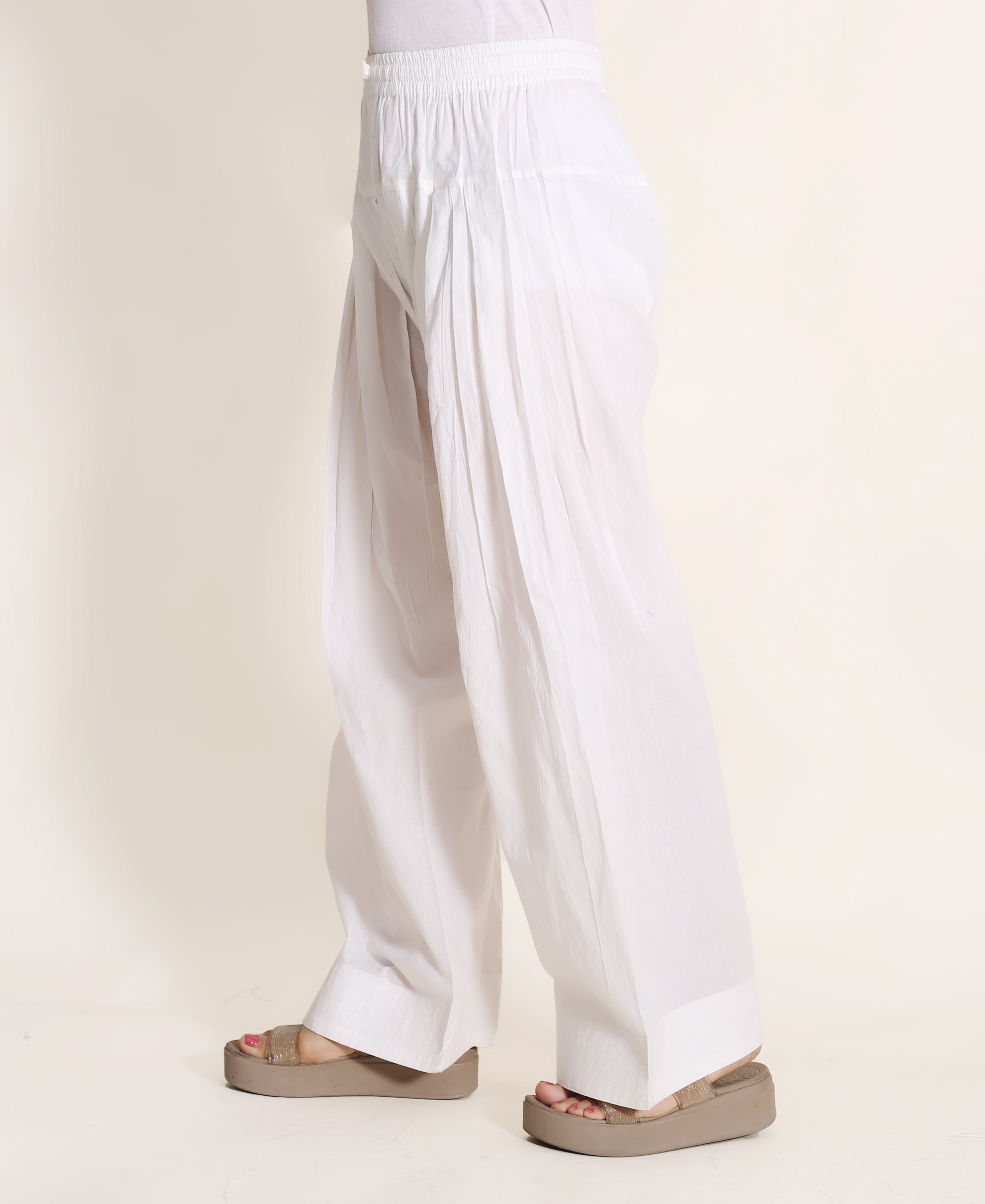 Side view of model wearing a comfortable, solid white pleated Farshi Salwar.