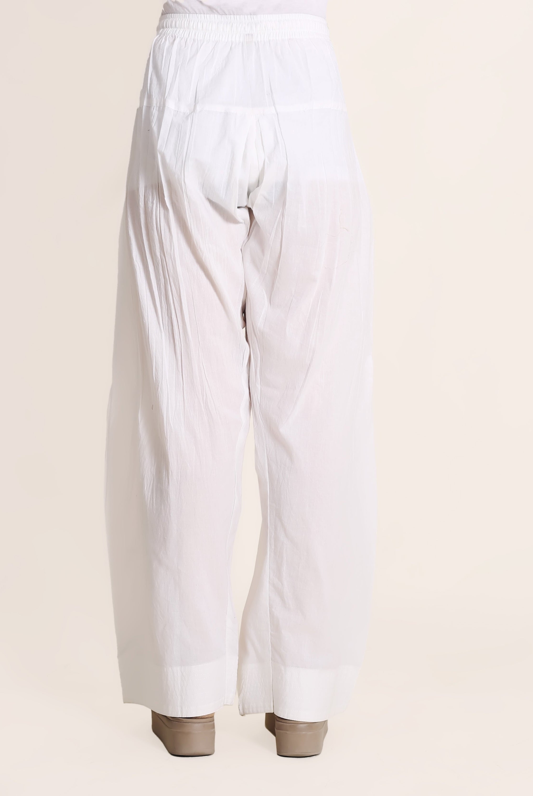 Back view of a model wearing solid white wide-legged Farshi Salwar with elasticated waist.