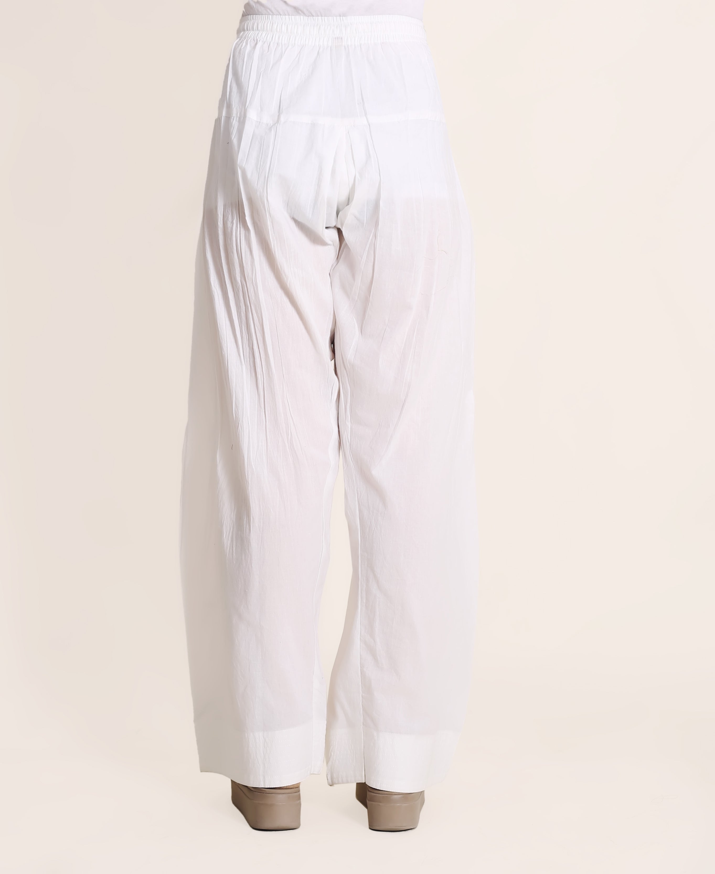 Back view of a model wearing solid white wide-legged Farshi Salwar with elasticated waist.