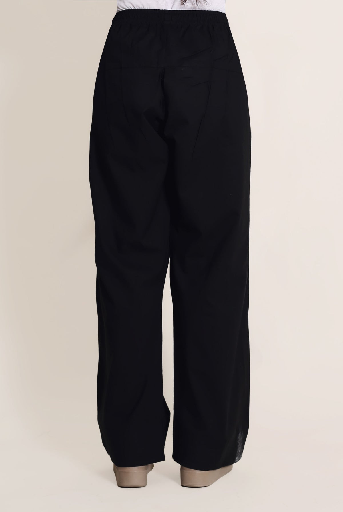 Solid black wide-legged trousers with no visible print, on a model with tan heels.