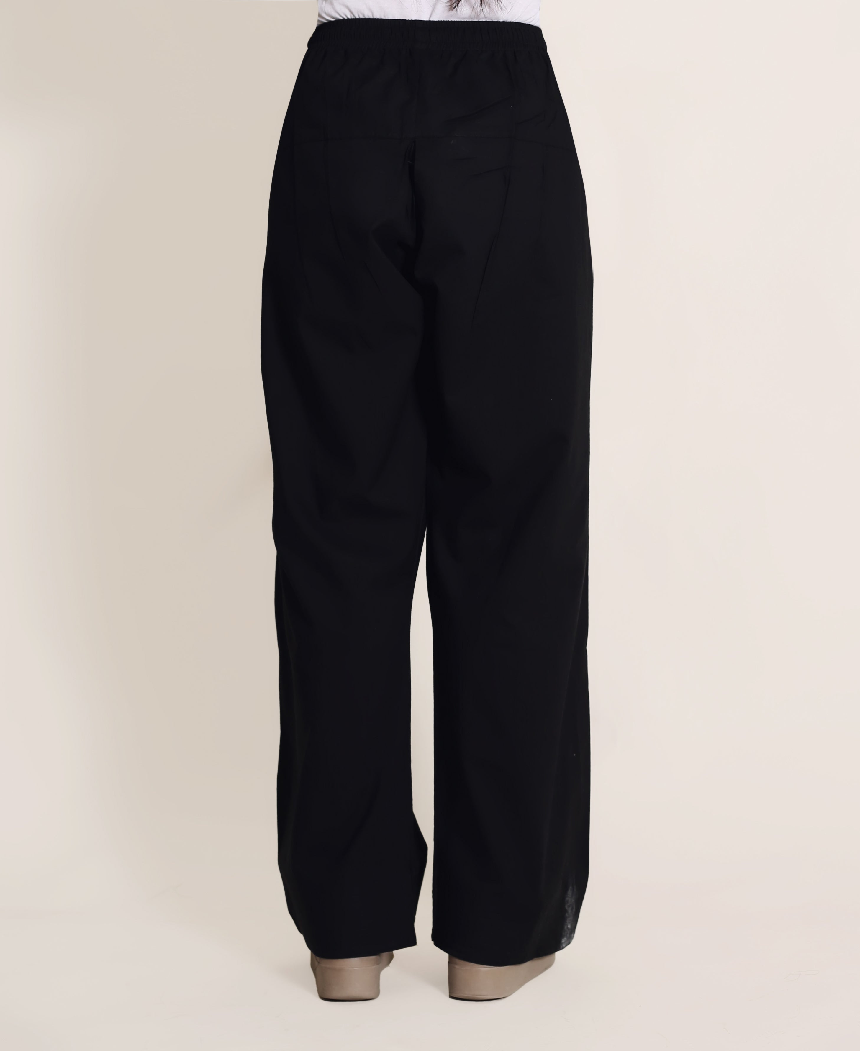 Solid black wide-legged trousers with no visible print, on a model with tan heels.