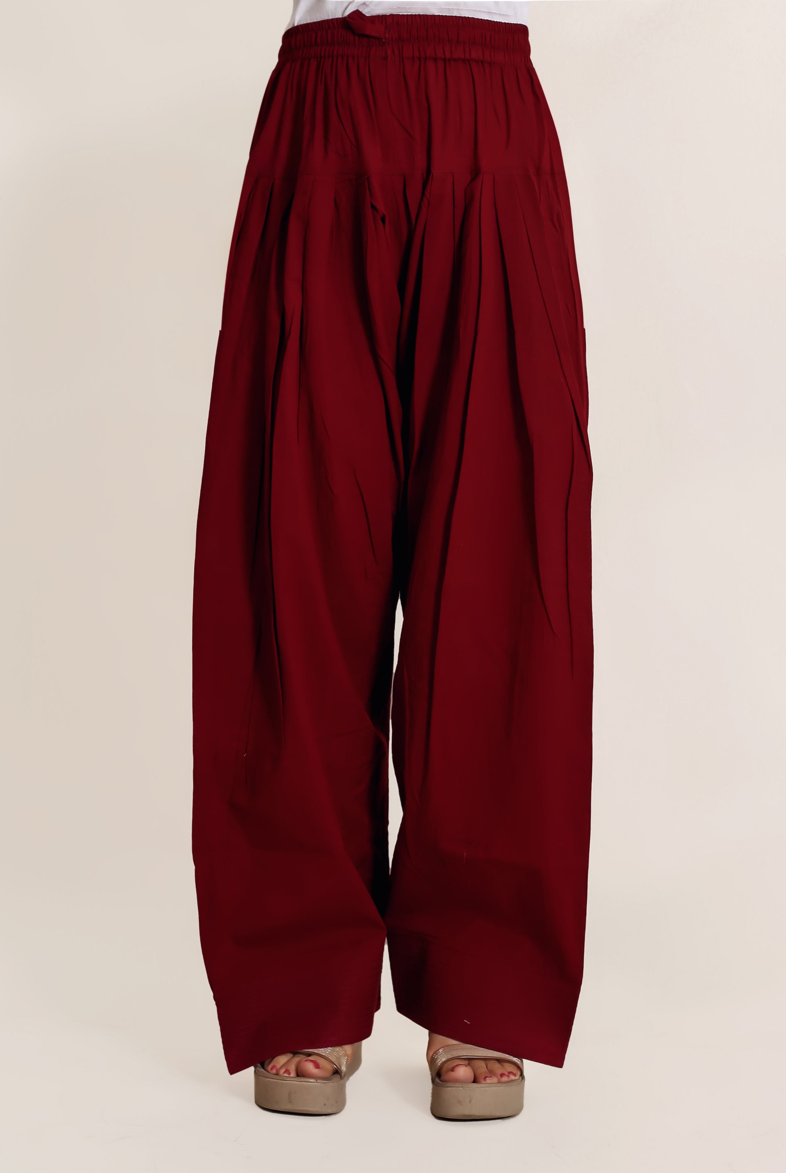 Front view of a model wearing a solid maroon pleated Farshi Salwar.