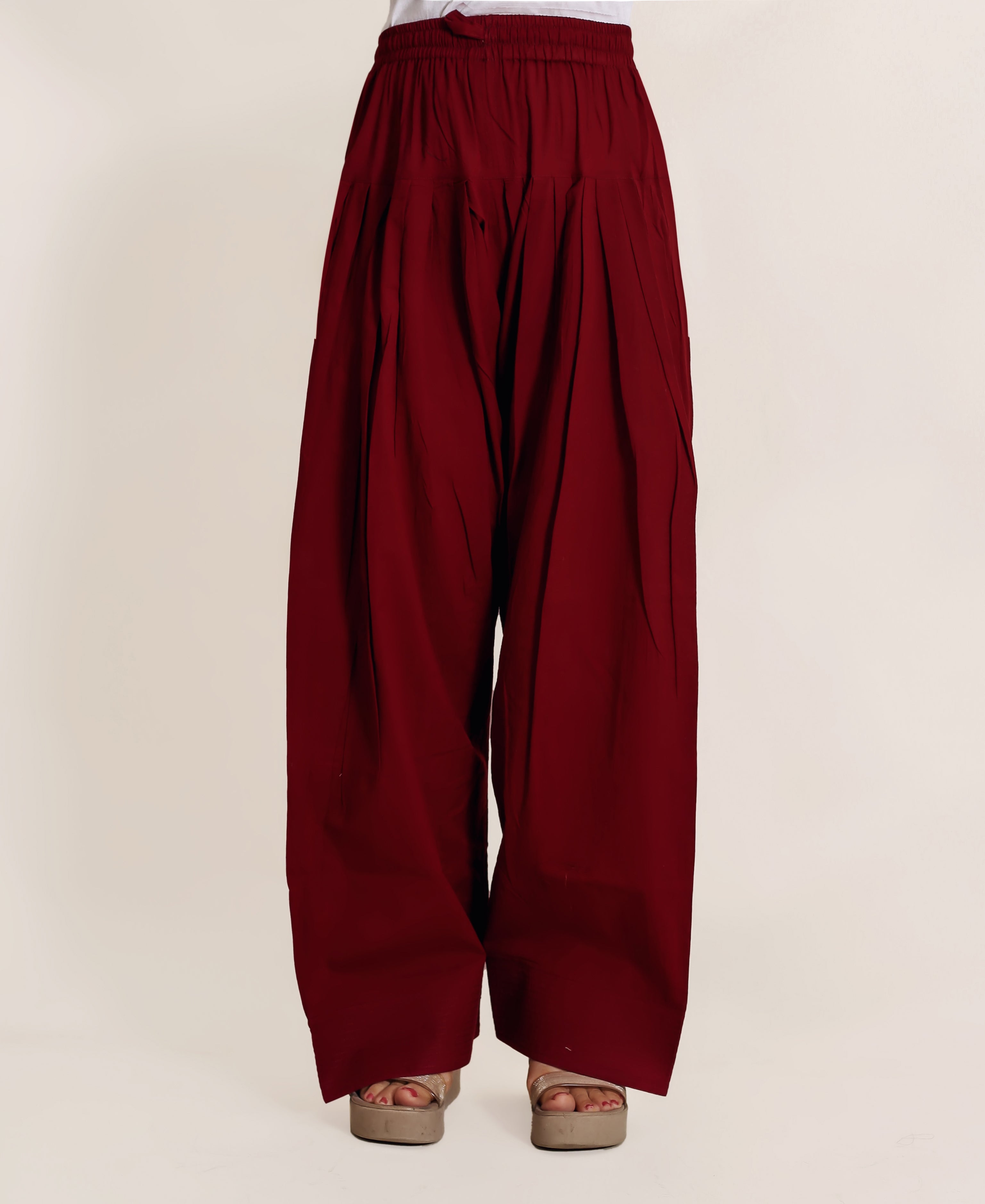 Front view of a model wearing a solid maroon pleated Farshi Salwar.