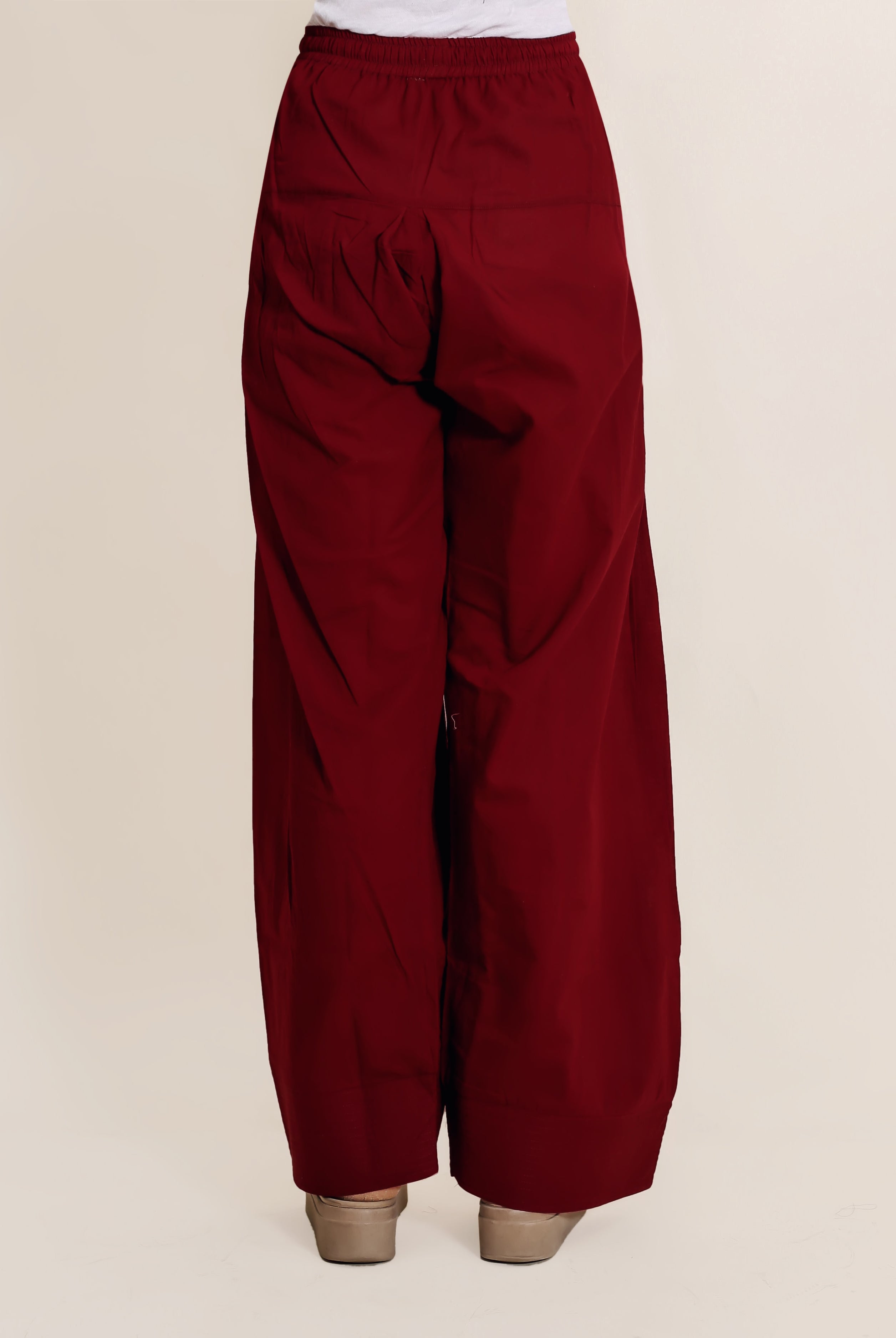 Back view of model wearing solid maroon wide-leg Farshi salwar with elastic waist.