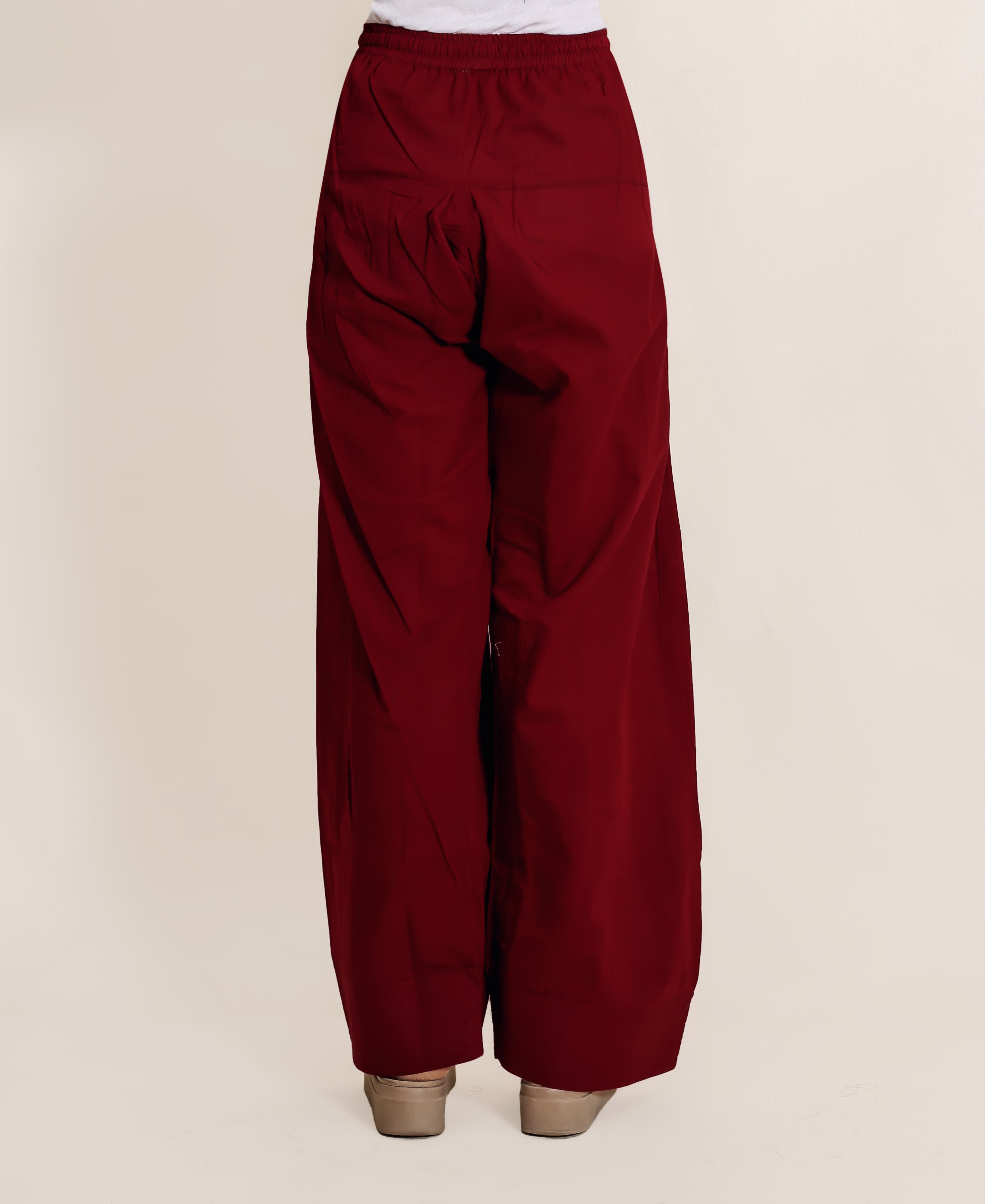 Back view of model wearing solid maroon wide-leg Farshi salwar with elastic waist.