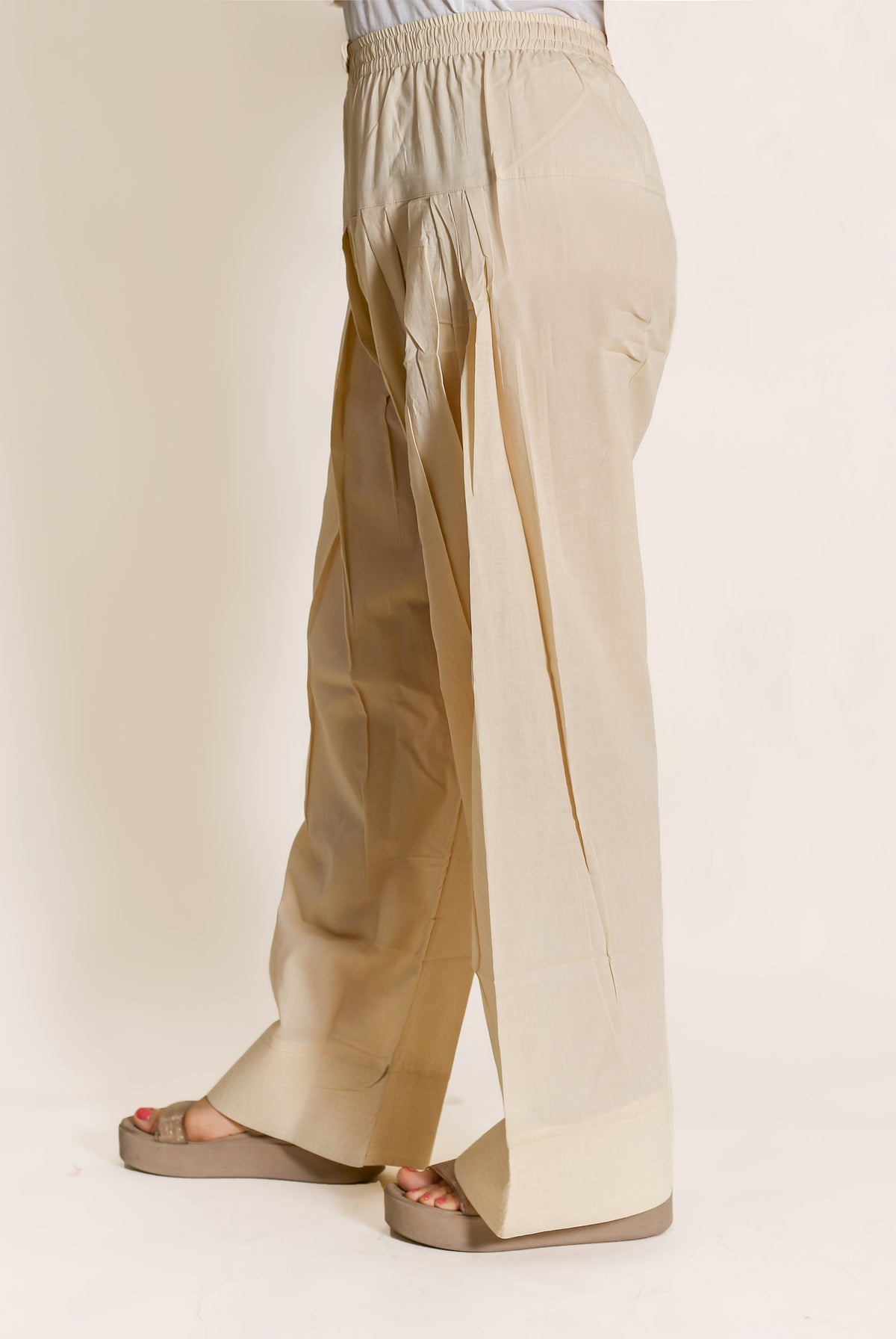 Beige salwar pants with hand-block print, model wearing sandals, solid neutral colour with no visible design.