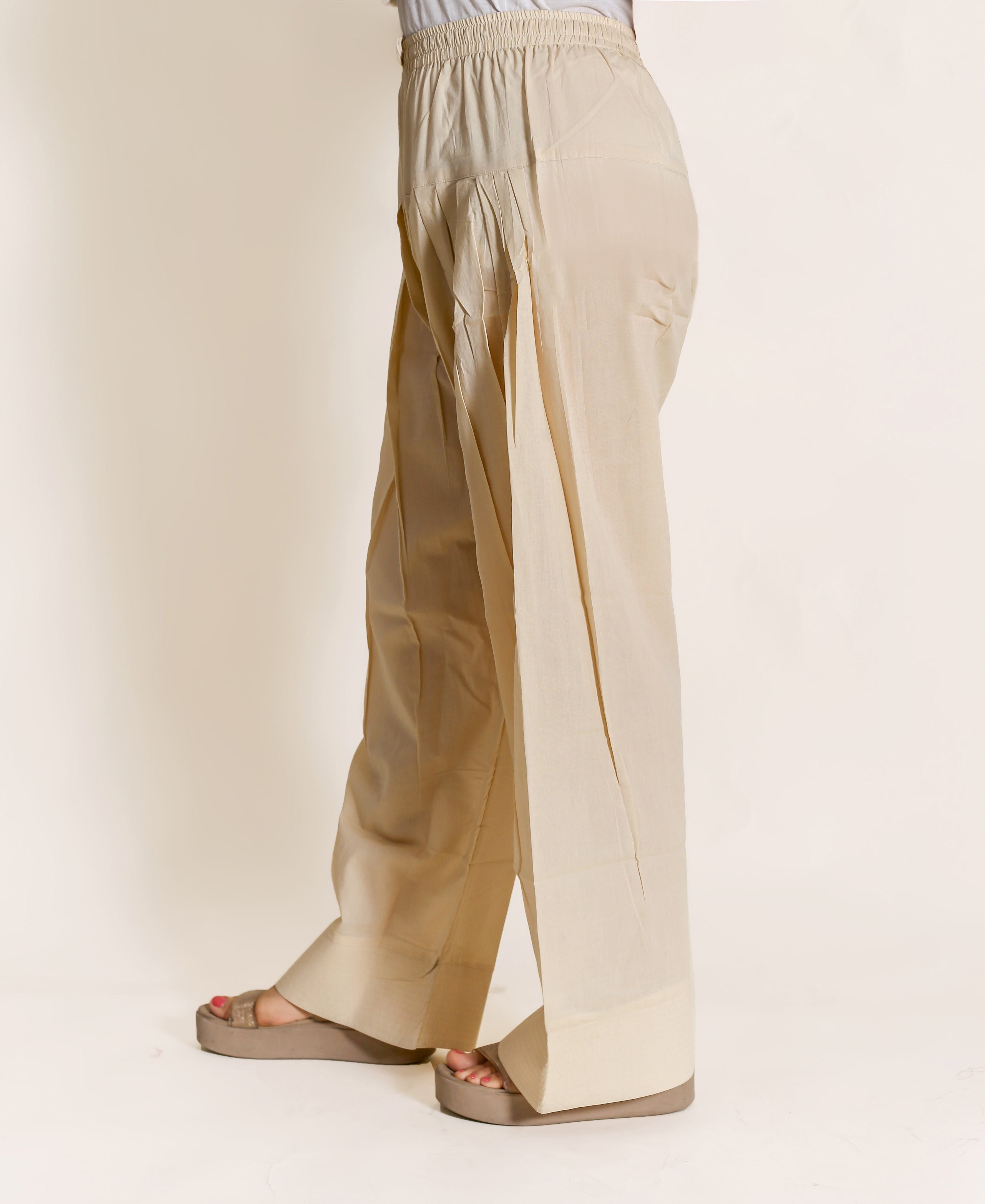 Beige salwar pants with hand-block print, model wearing sandals, solid neutral colour with no visible design.