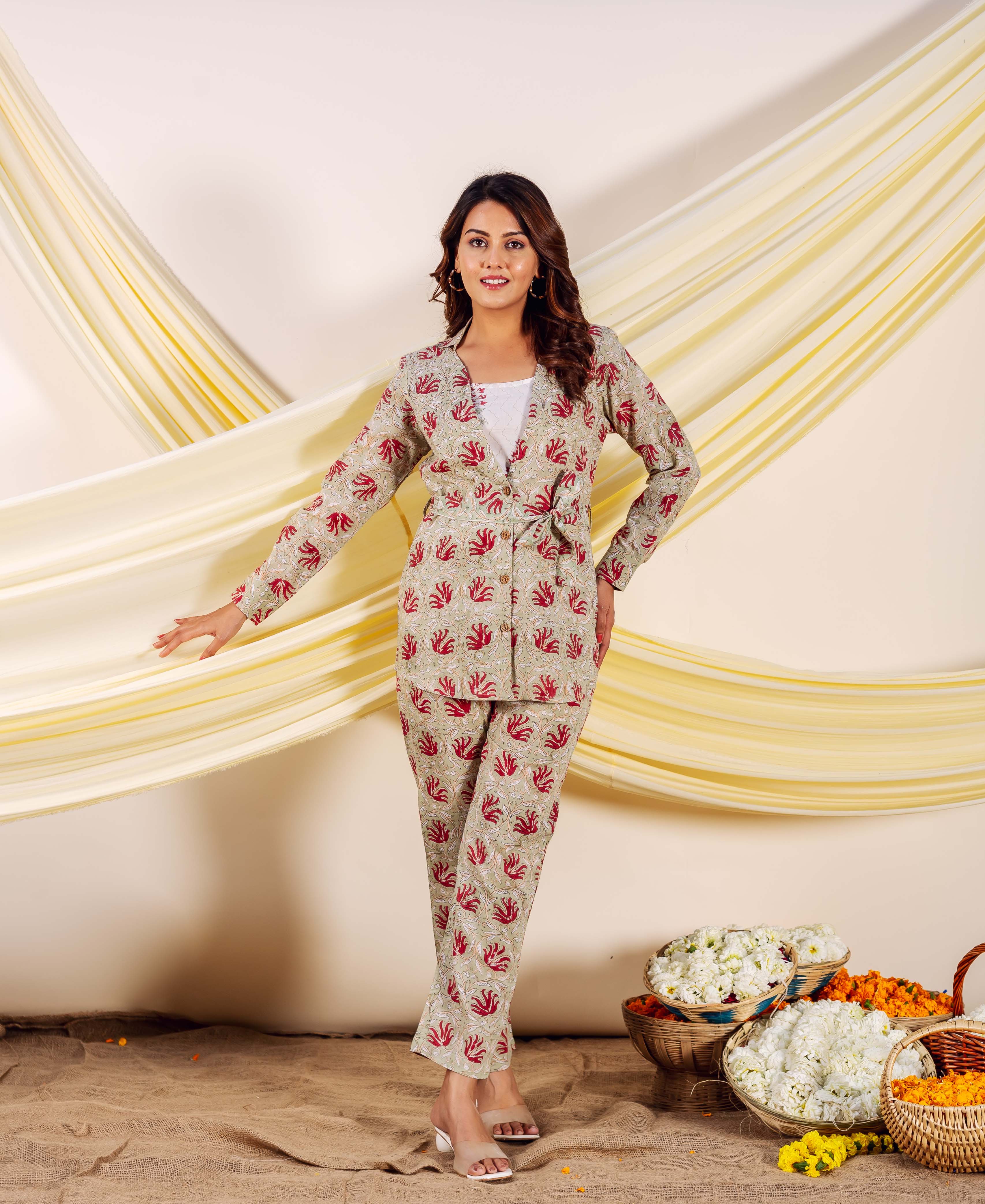 Woman modeling a light beige matching top and pants with red ethnic block print.