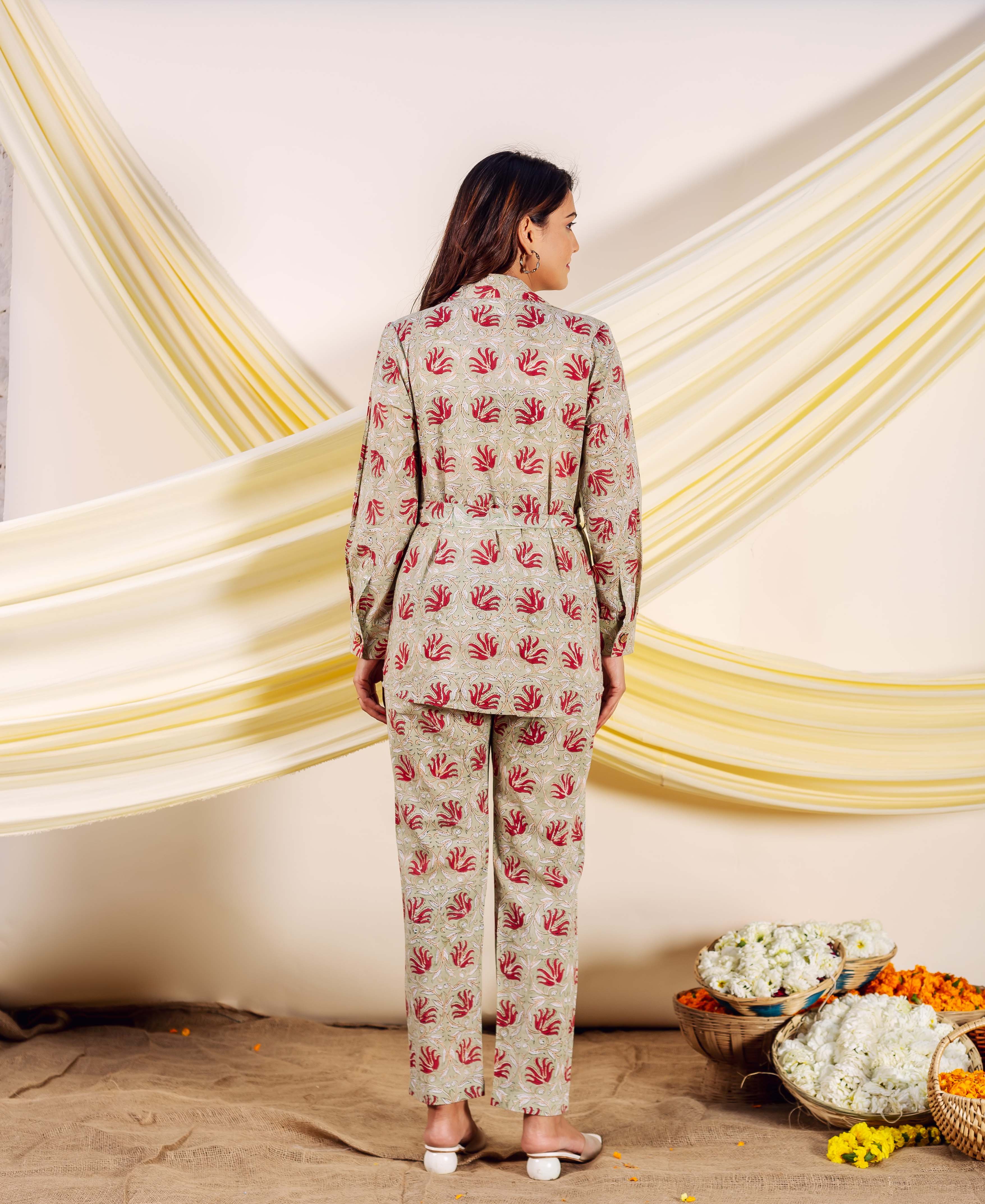 Model from back in a greige hand-block printed co-ord set with red motifs and belt.