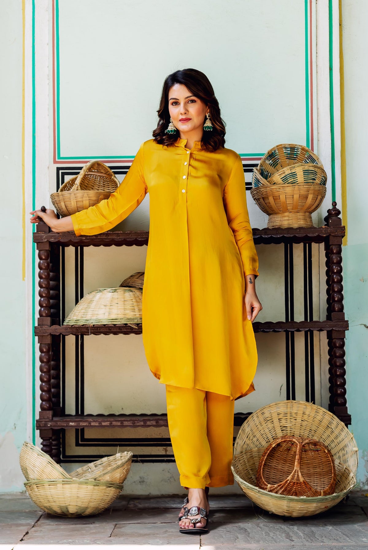 A woman in a yellow satin coord set with a high-low hem and white buttons.