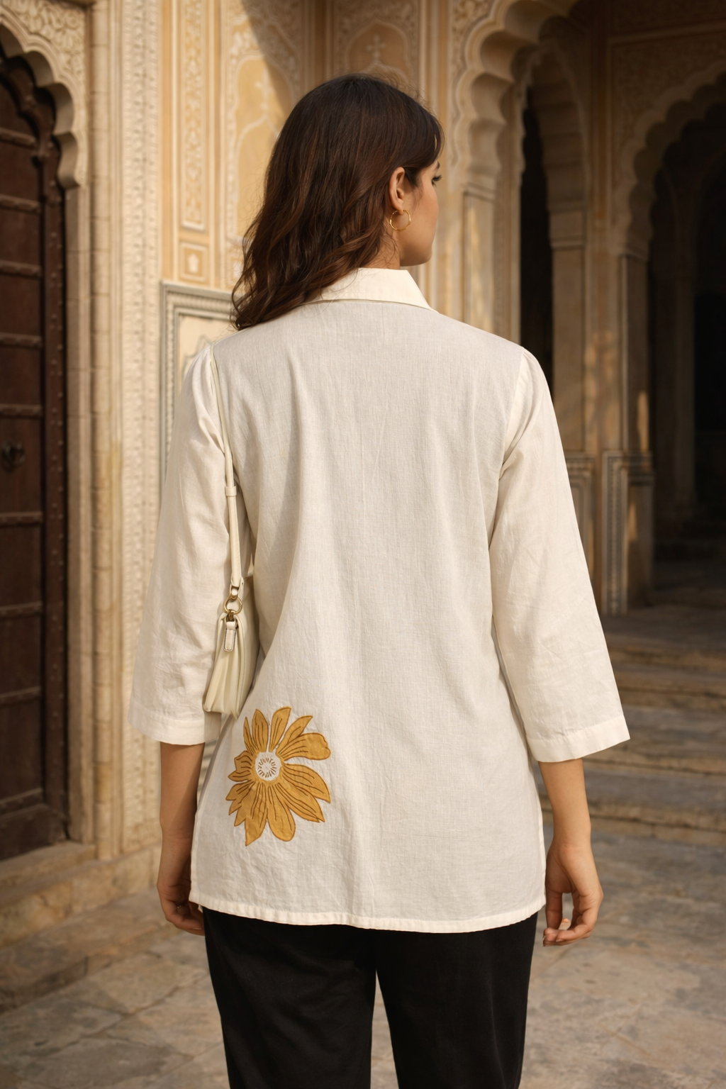 Rear view of model in cream cotton shirt featuring large mustard floral block print.