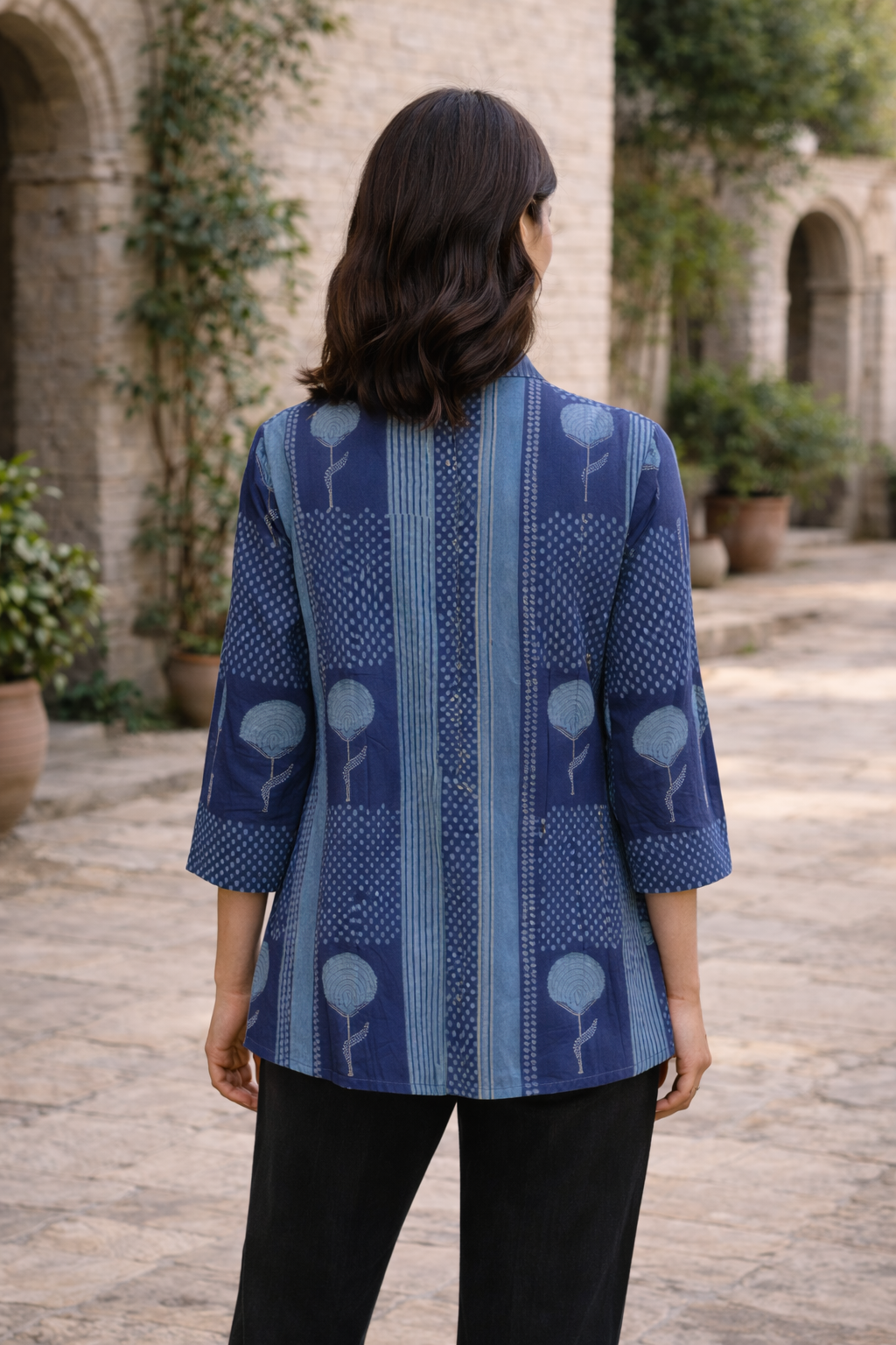 Rear view of model wearing a midnight blue hand-block-printed ethnic top with floral and striped patterns.