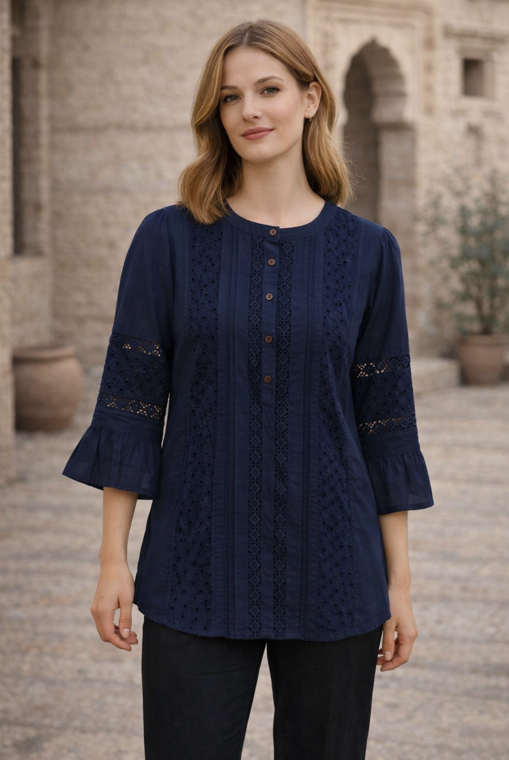 Model wears indigo blue top with eyelet lace, pintucks, and 3/4 ruffled sleeves.
