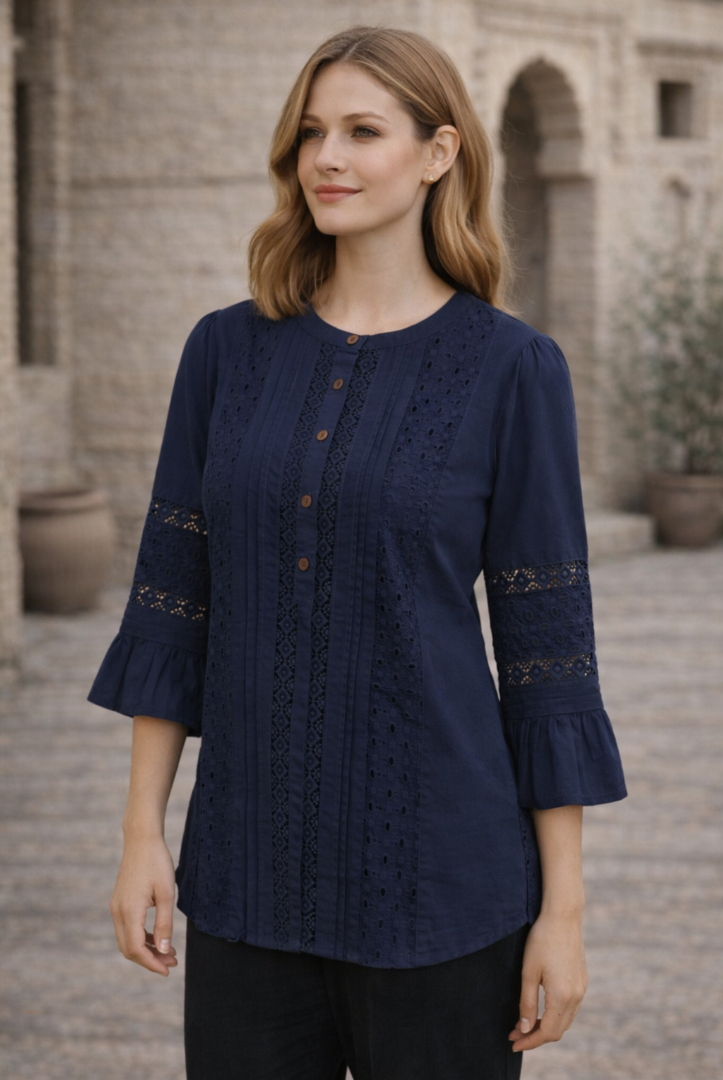 Front shot of model in an indigo lace top with pintucks and three-quarter bell sleeves.