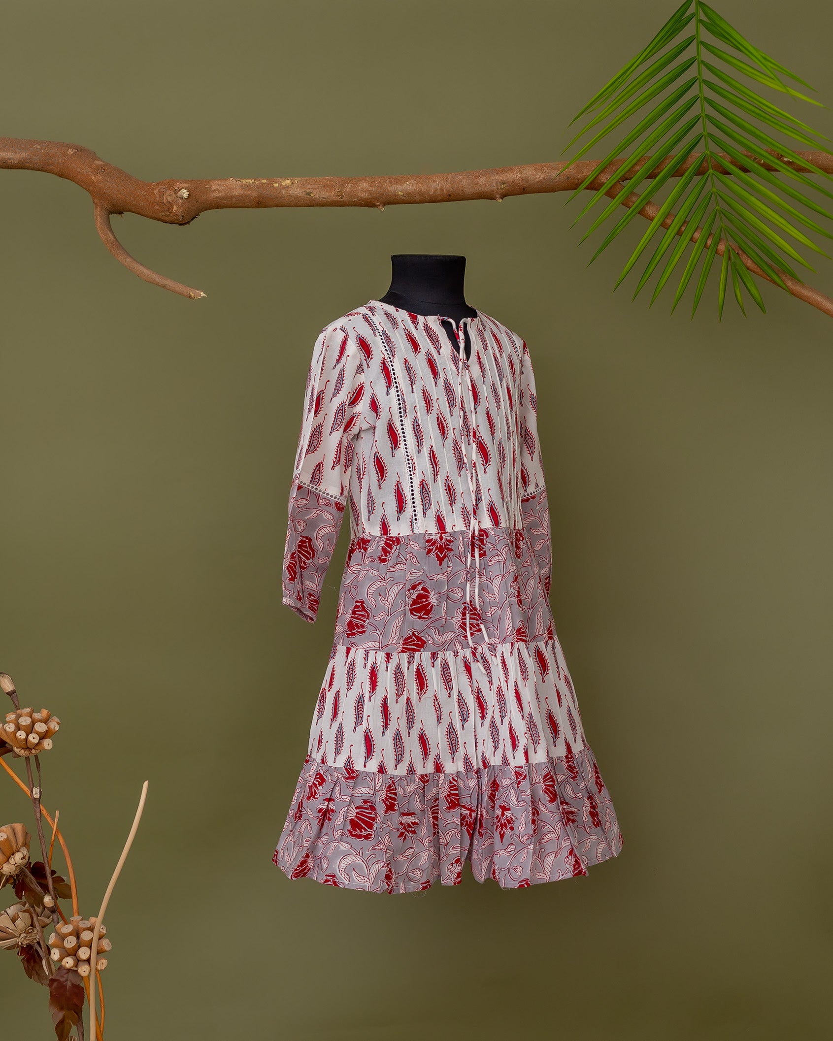 Grey and pink tiered dress with red floral print on a black mannequin.