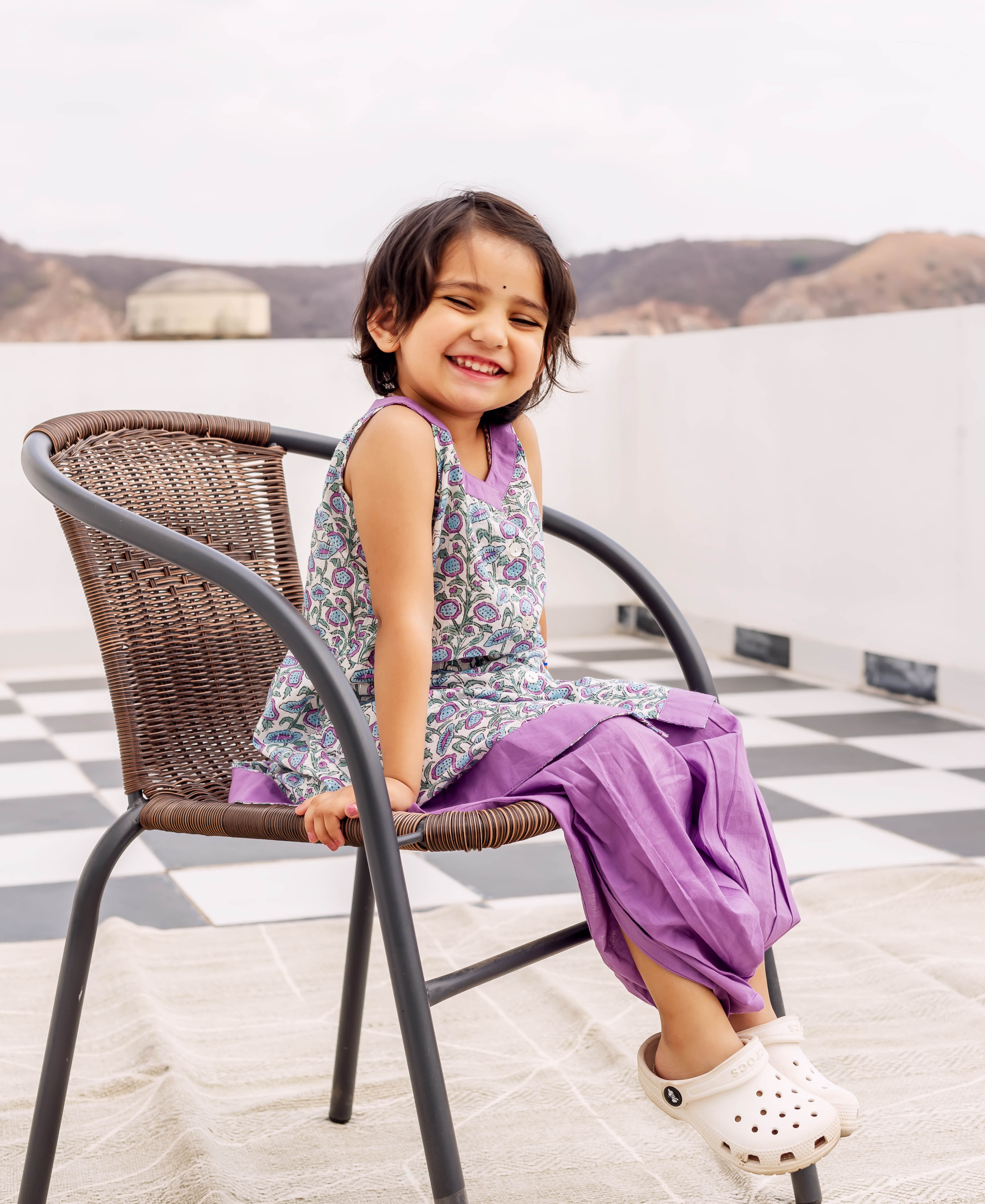 Smiling girl in a sleeveless hand block printed cotton kurta and vibrant purple dhoti.