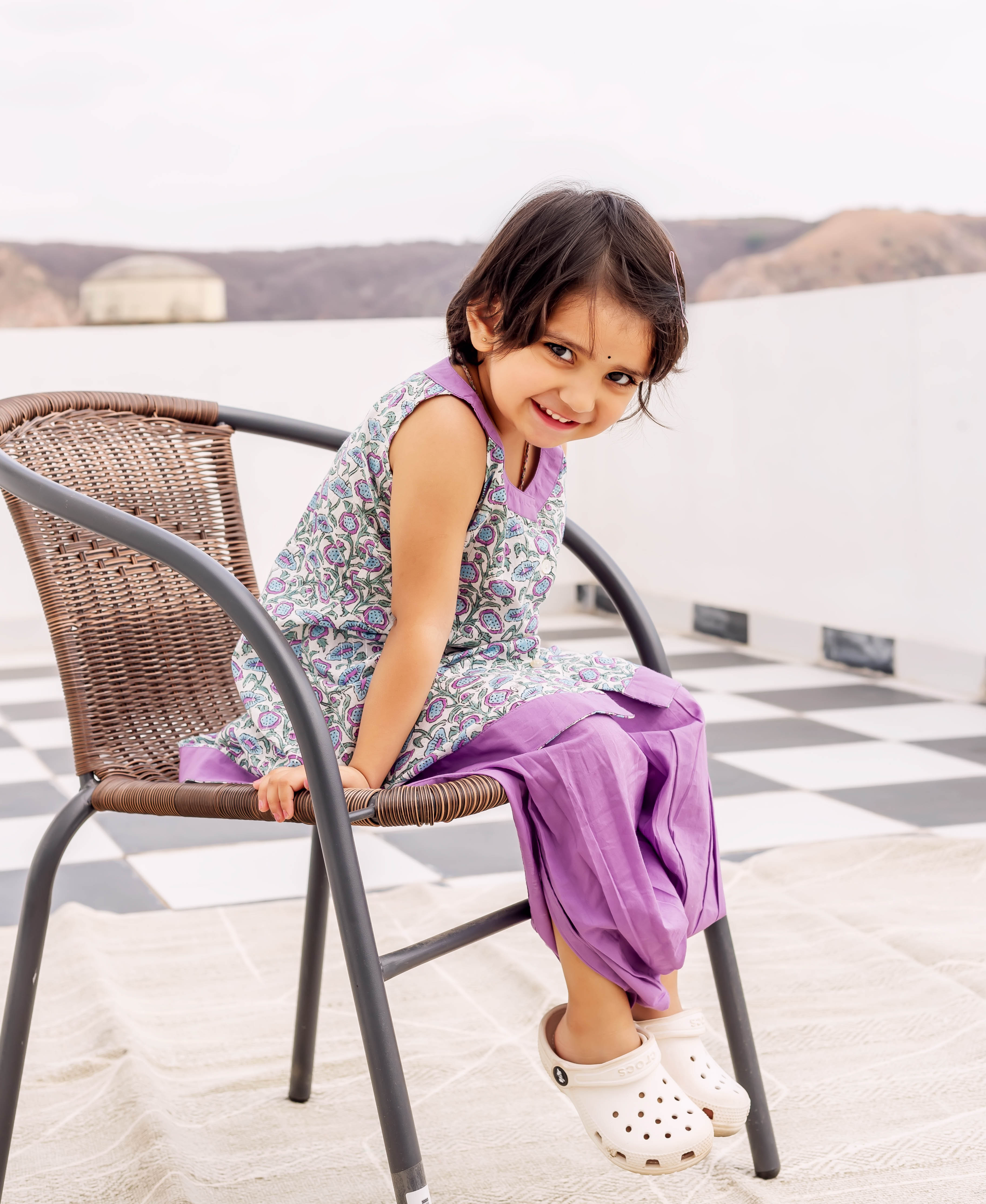 Smiling child wearing purple and floral hand block printed cotton kurta with matching dhoti.