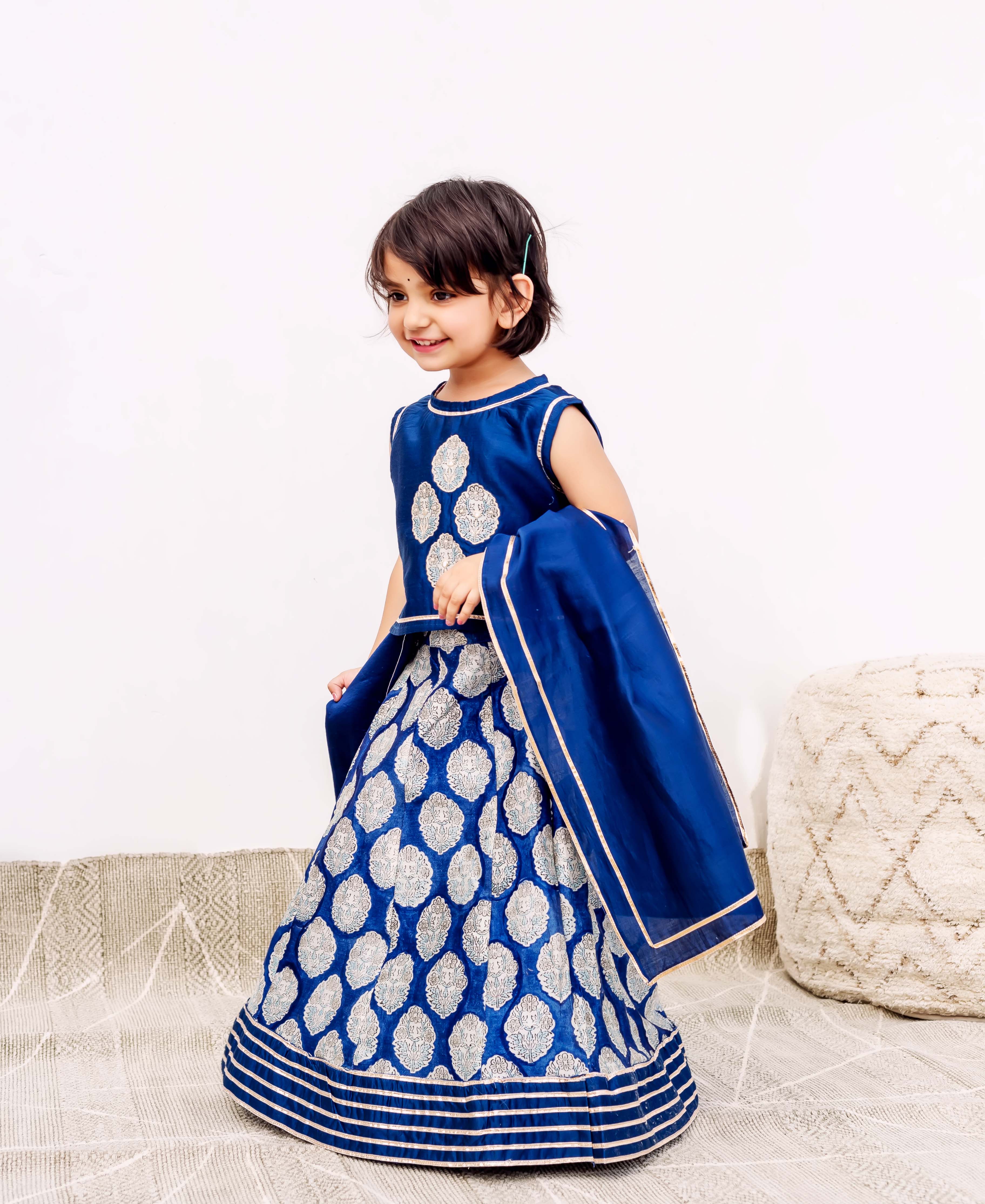 Young girl wearing a royal blue silk lehenga with silver patterns and a matching dupatta.