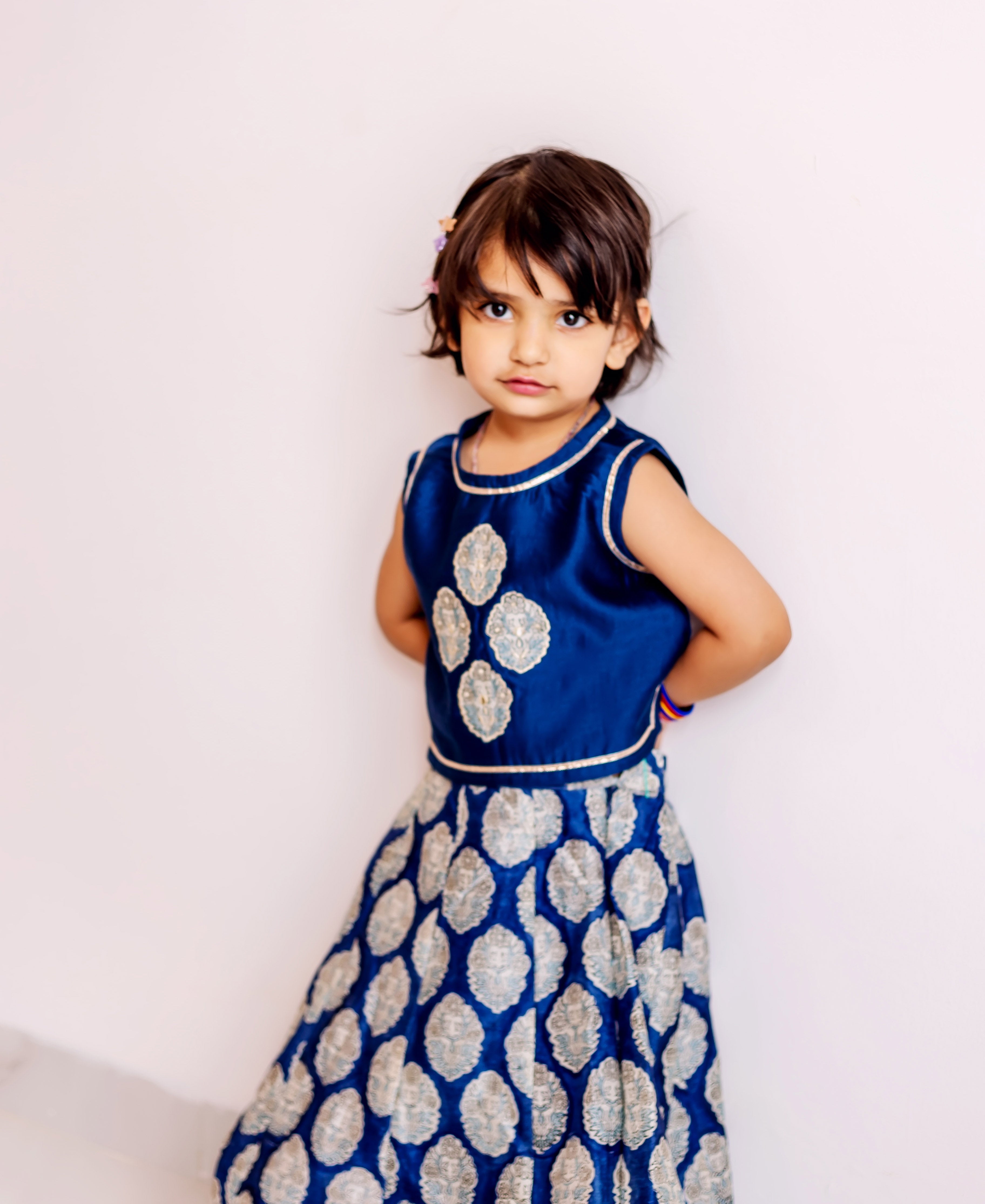 Young girl modeling a blue silk lehenga choli with silver patterned print.
