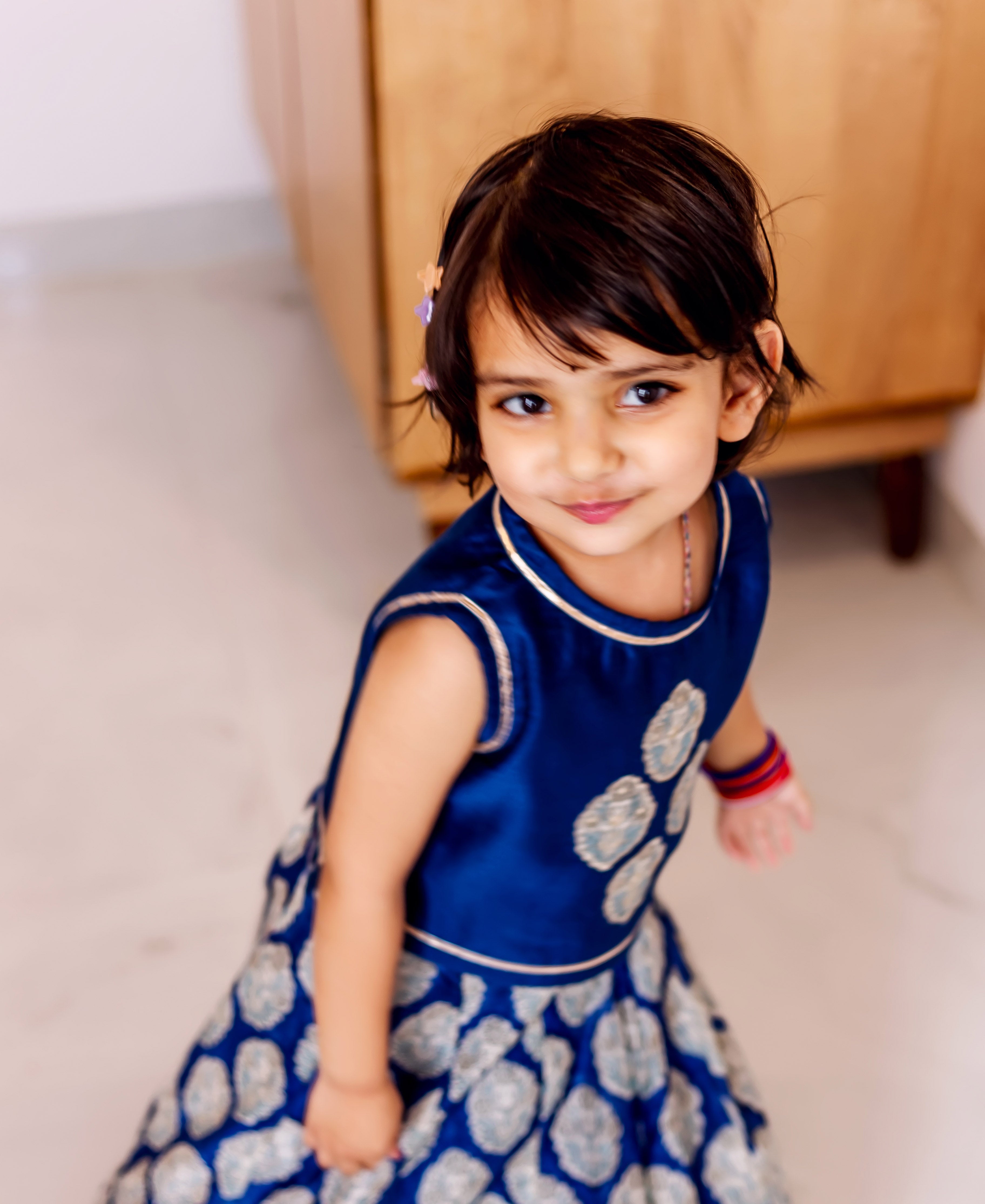 Young girl in top-down view, wearing blue silk lehenga with patterned print skirt.