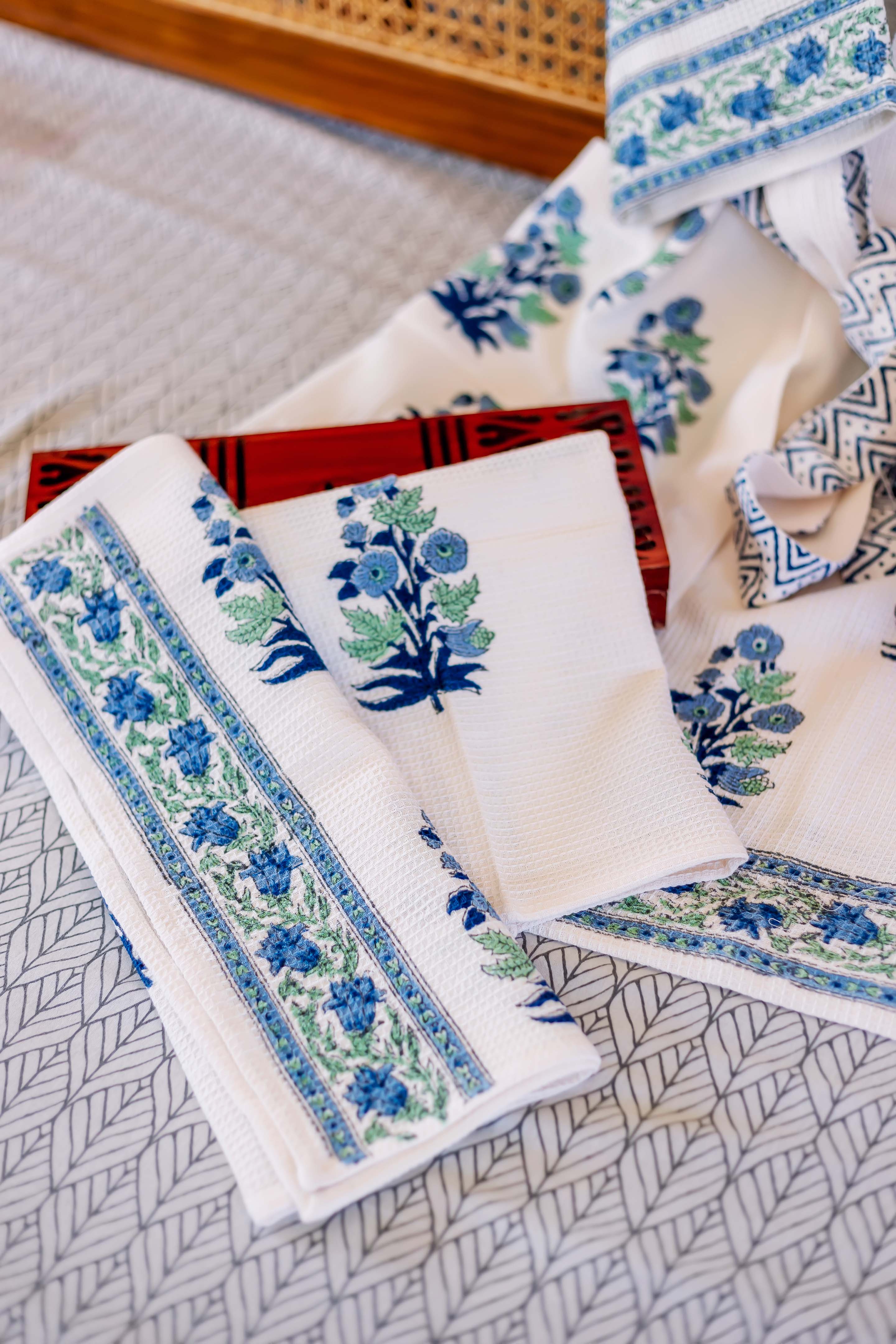 White waffle-weave hand towels with blue and green hand-block floral patterns.