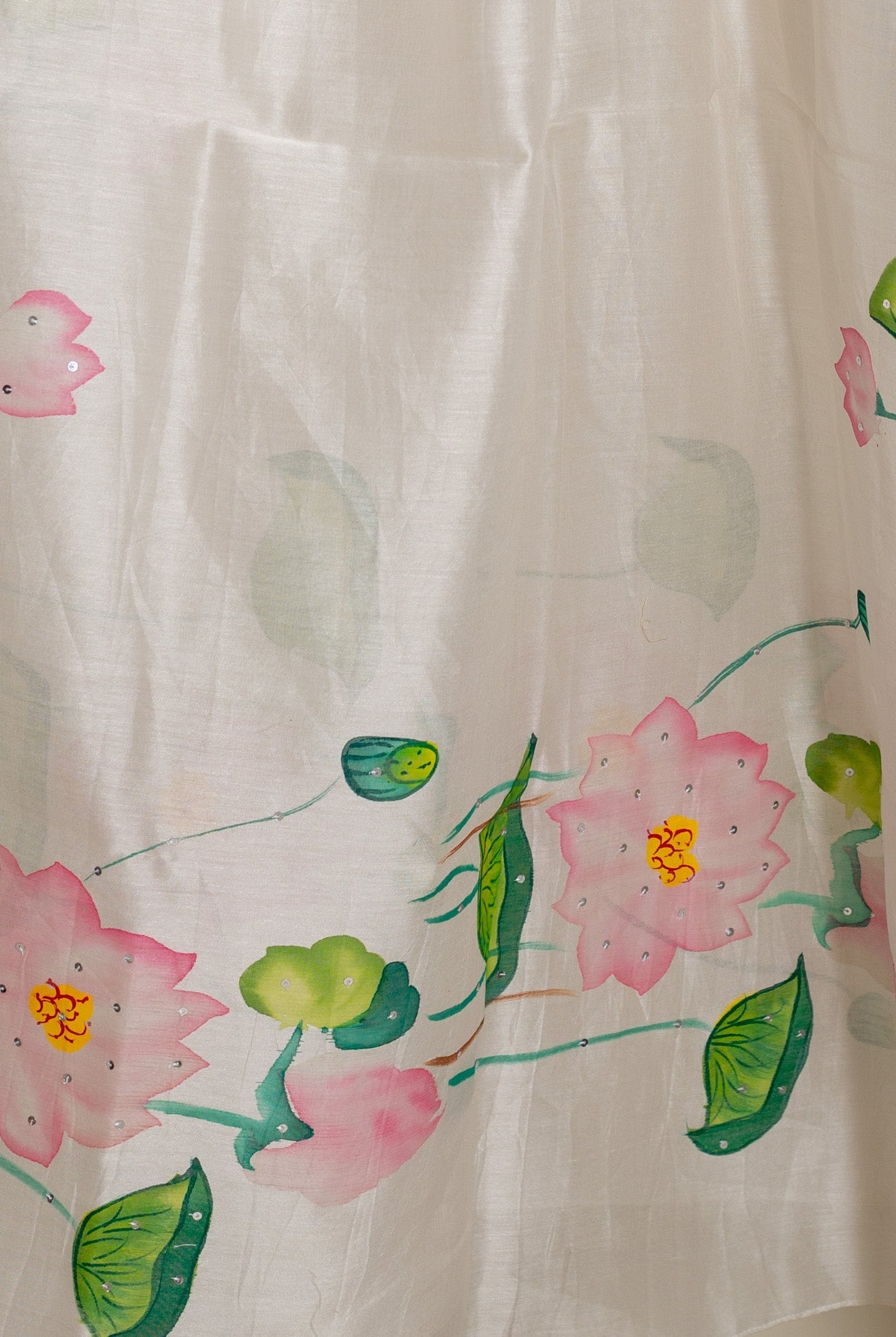 A close-up of a white, hand-painted floral kurta with pink lotus flowers and green leaves.