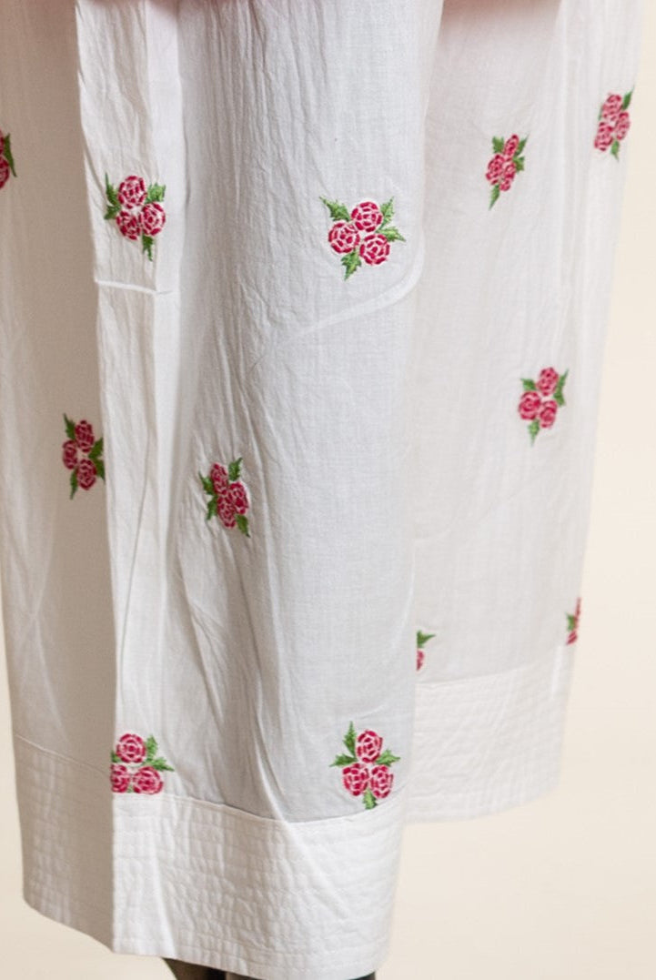 Close-up of white cotton salwar leg with fuchsia pink rose embroidery.