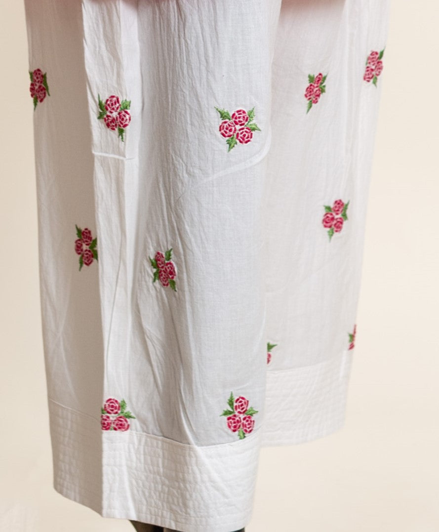 Close-up of white cotton salwar leg with fuchsia pink rose embroidery.