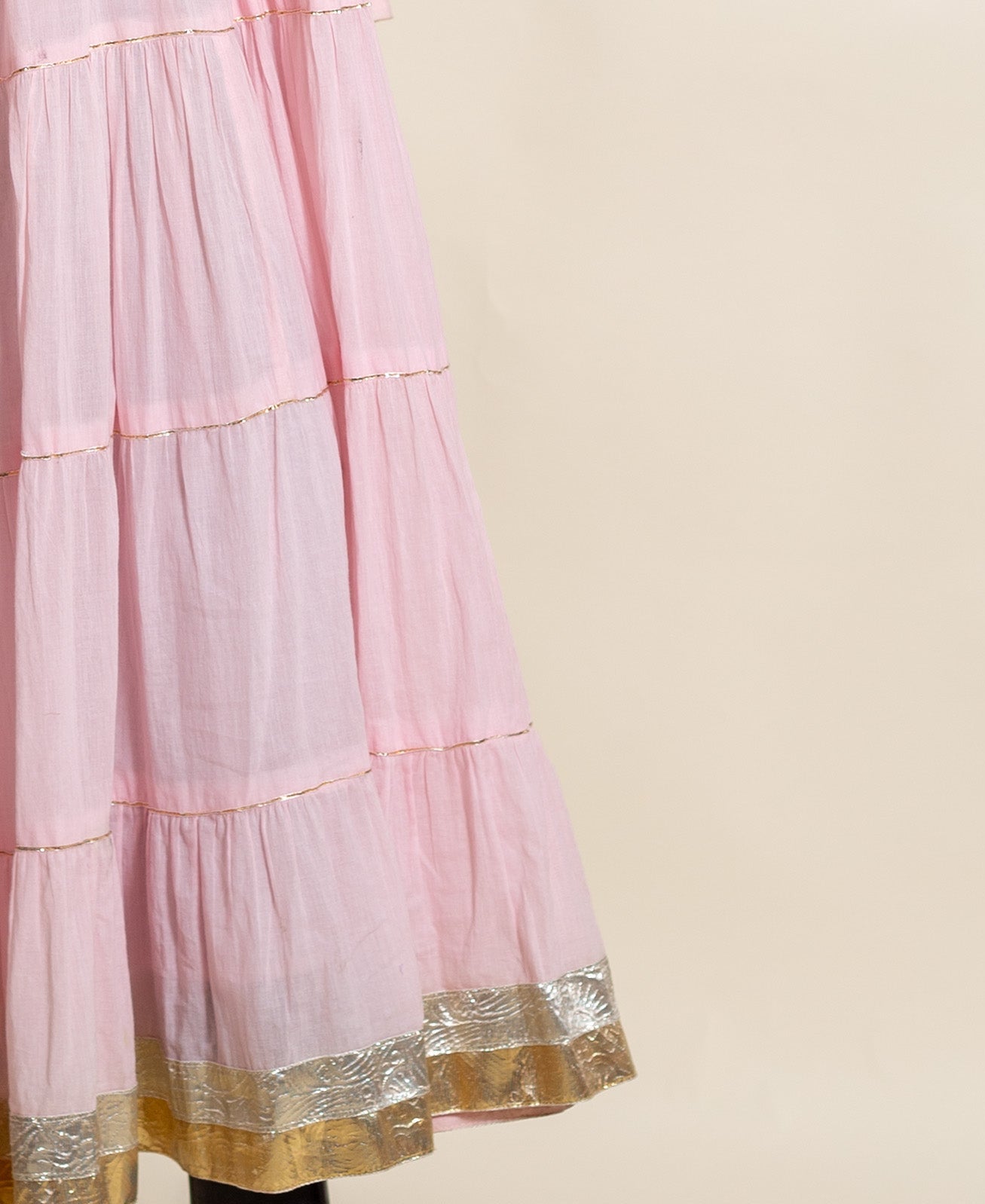 Pink tiered cotton dress with gold-trimmed seams and metallic patterned hem.