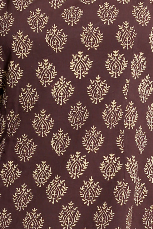Close-up of brown handblock cotton fabric with repeating cream stylized floral print.
