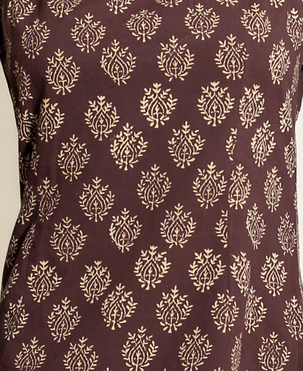 Close-up of brown handblock cotton fabric with repeating cream stylized floral print.