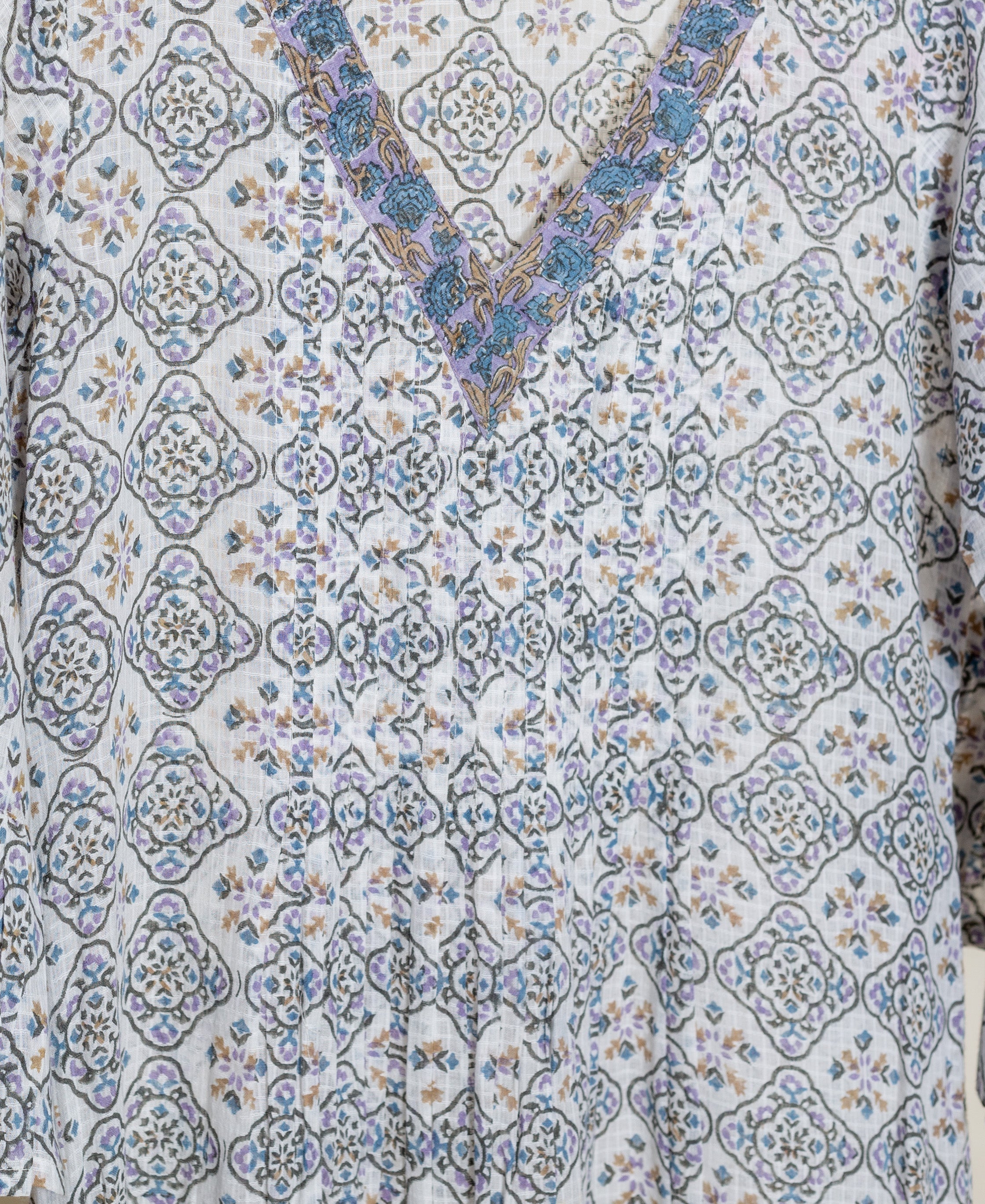 White handblock dress with multicolour floral-geometric print, embroidered V-neck, and pleated yoke.