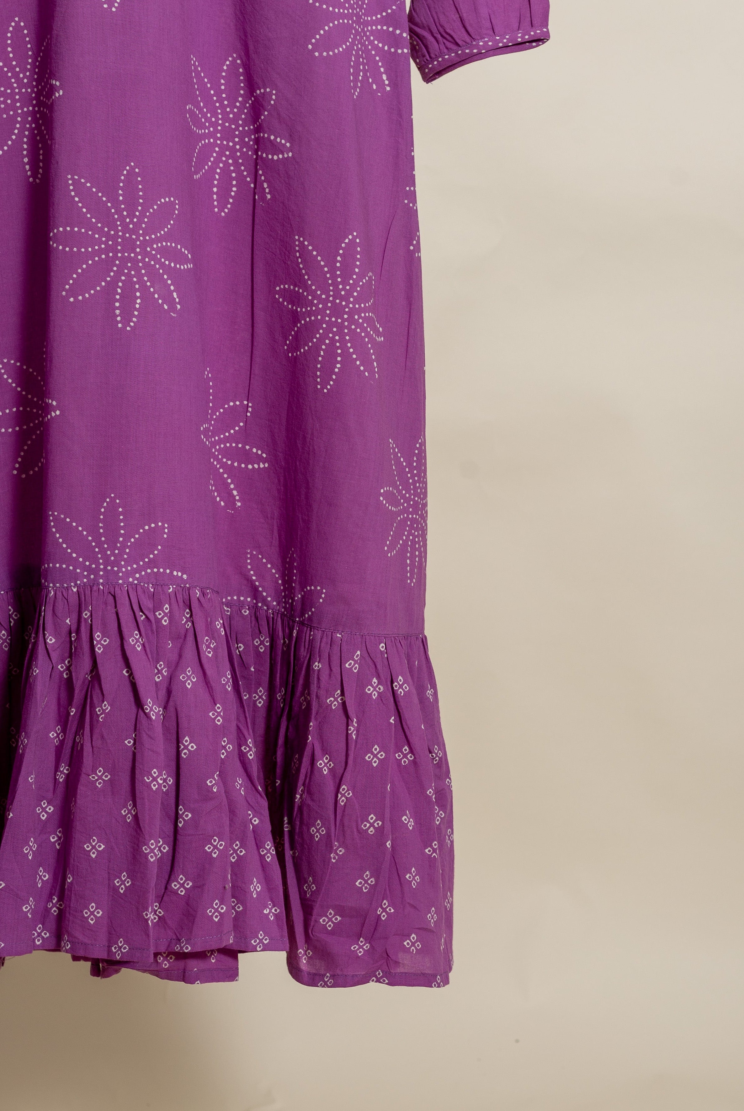 Flat lay of a lilac dress with white bandhej print and ruffled hem.