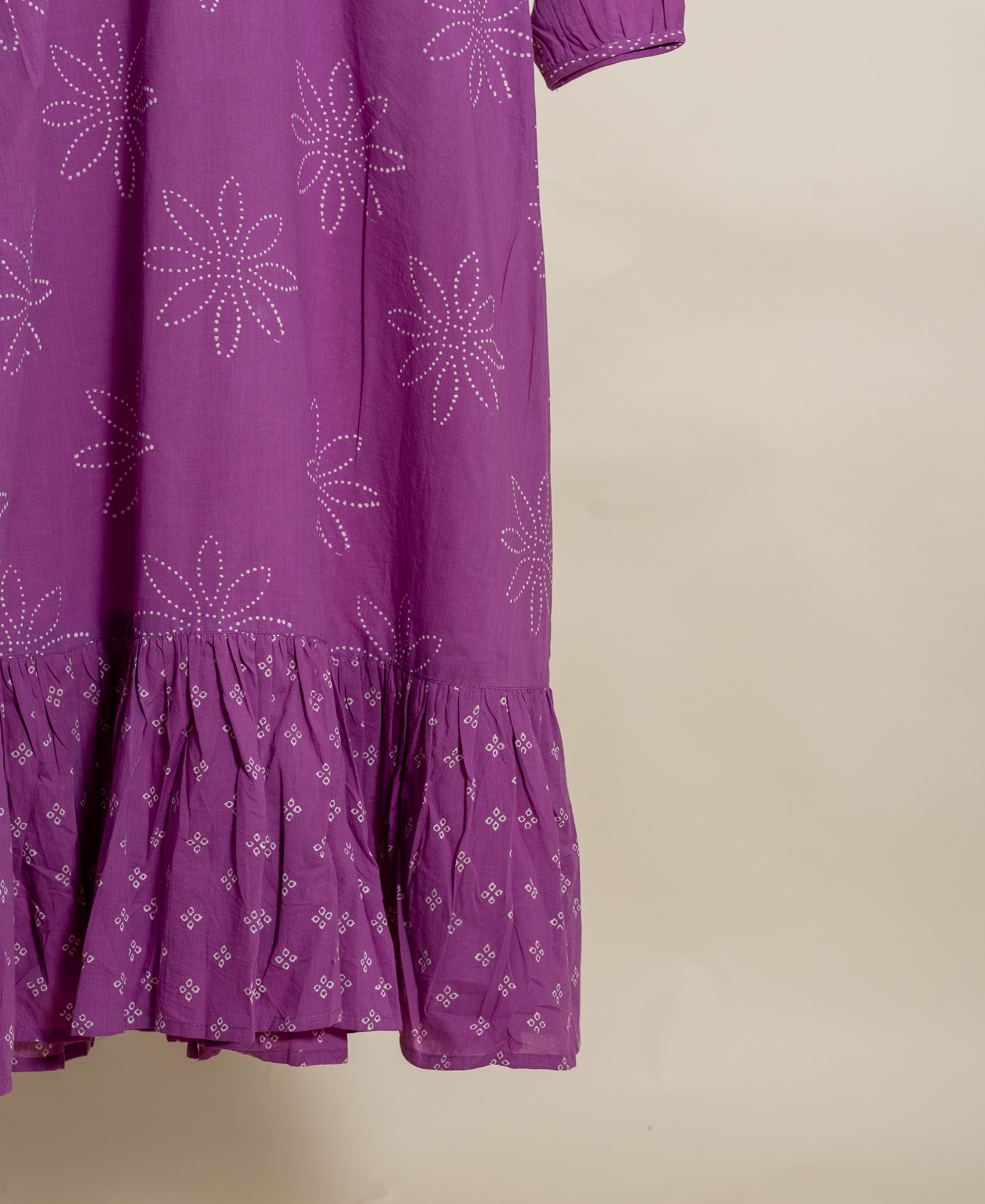Flat lay of a lilac dress with white bandhej print and ruffled hem.