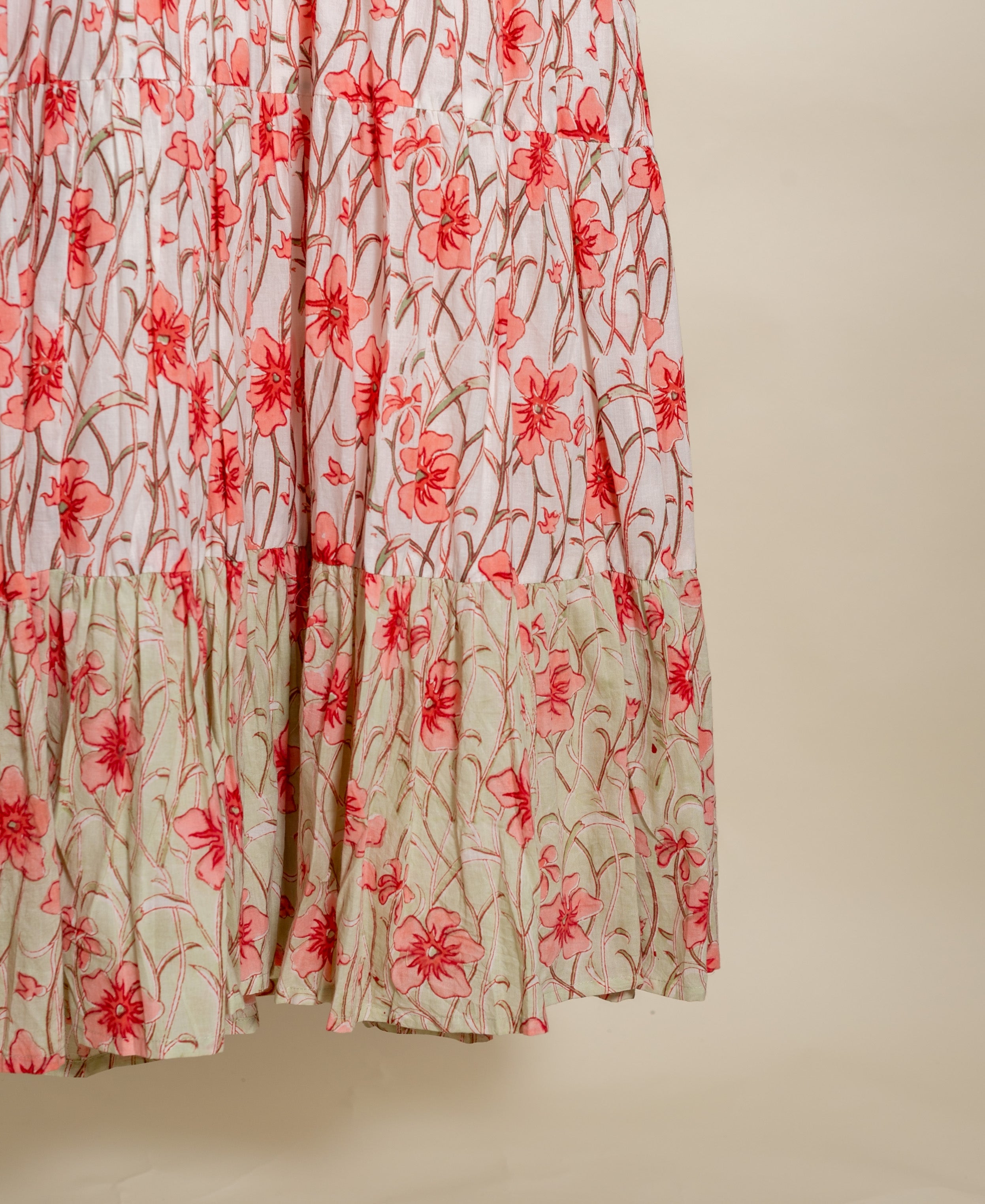 A peach floral print dress with a white background and a tiered design.