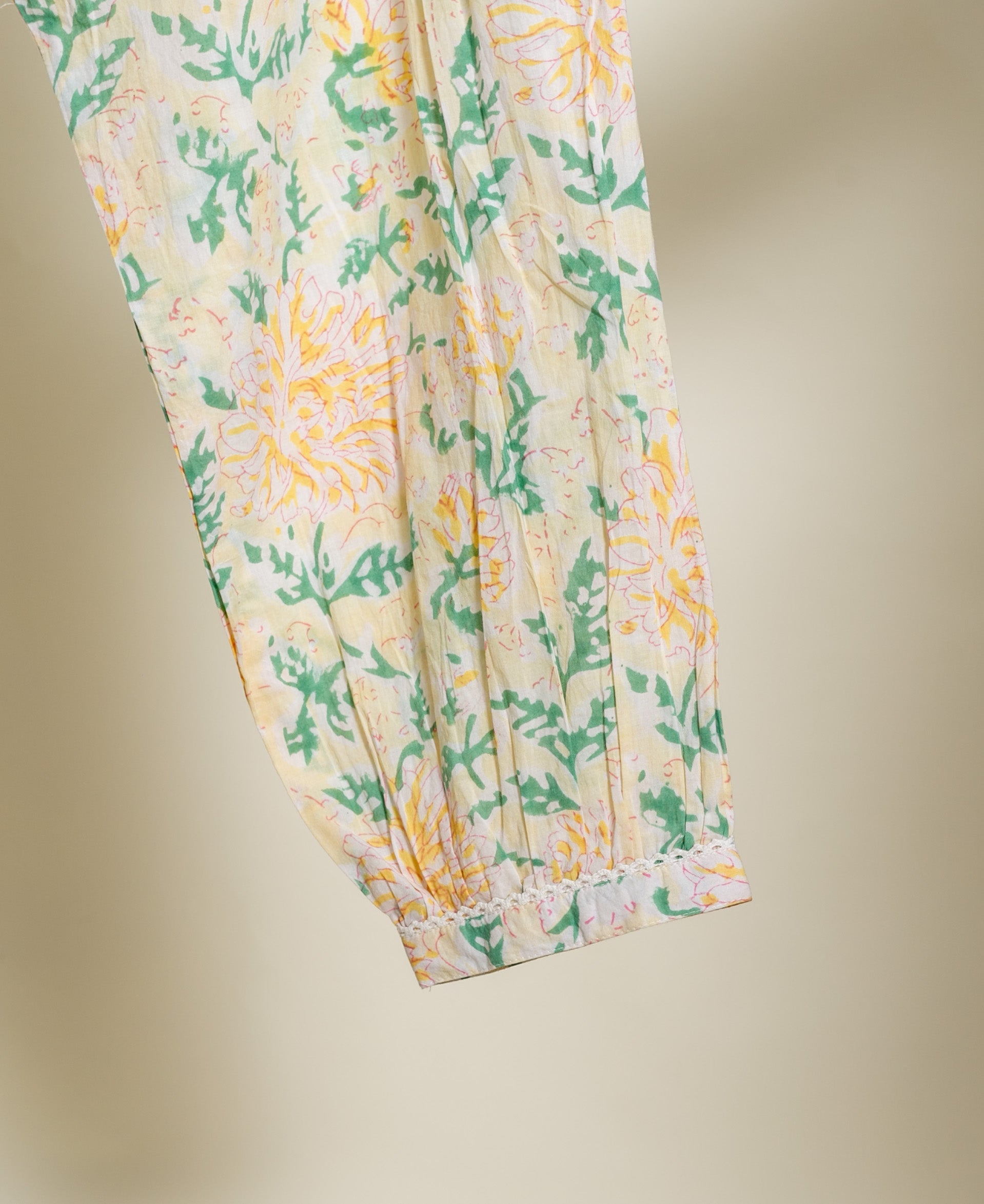 Draped ivory cotton garment with yellow and green botanical print and delicate lace trim.