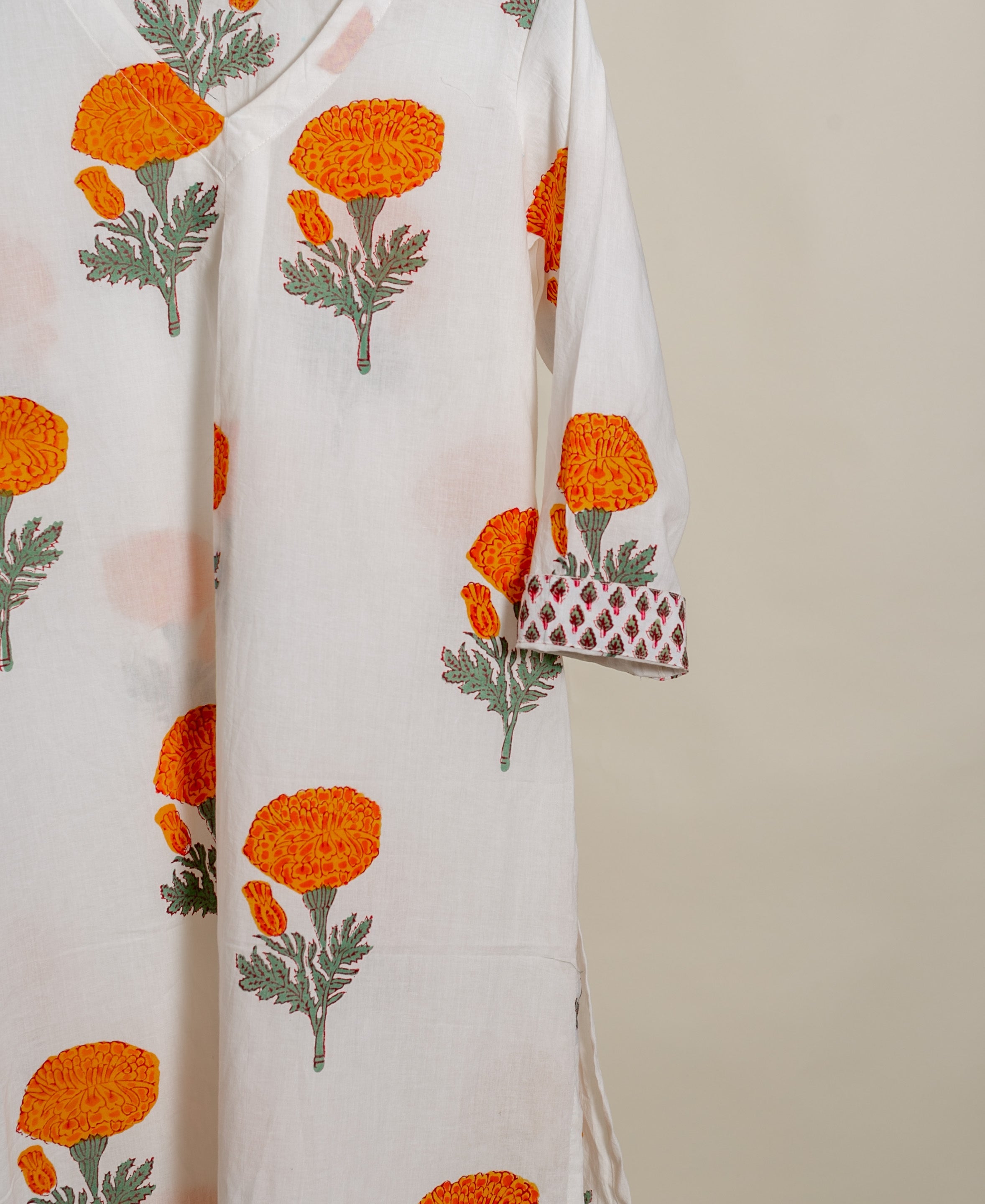 Close-up of ivory kurta with orange marigold handblock print and geometric patterned sleeve cuff.