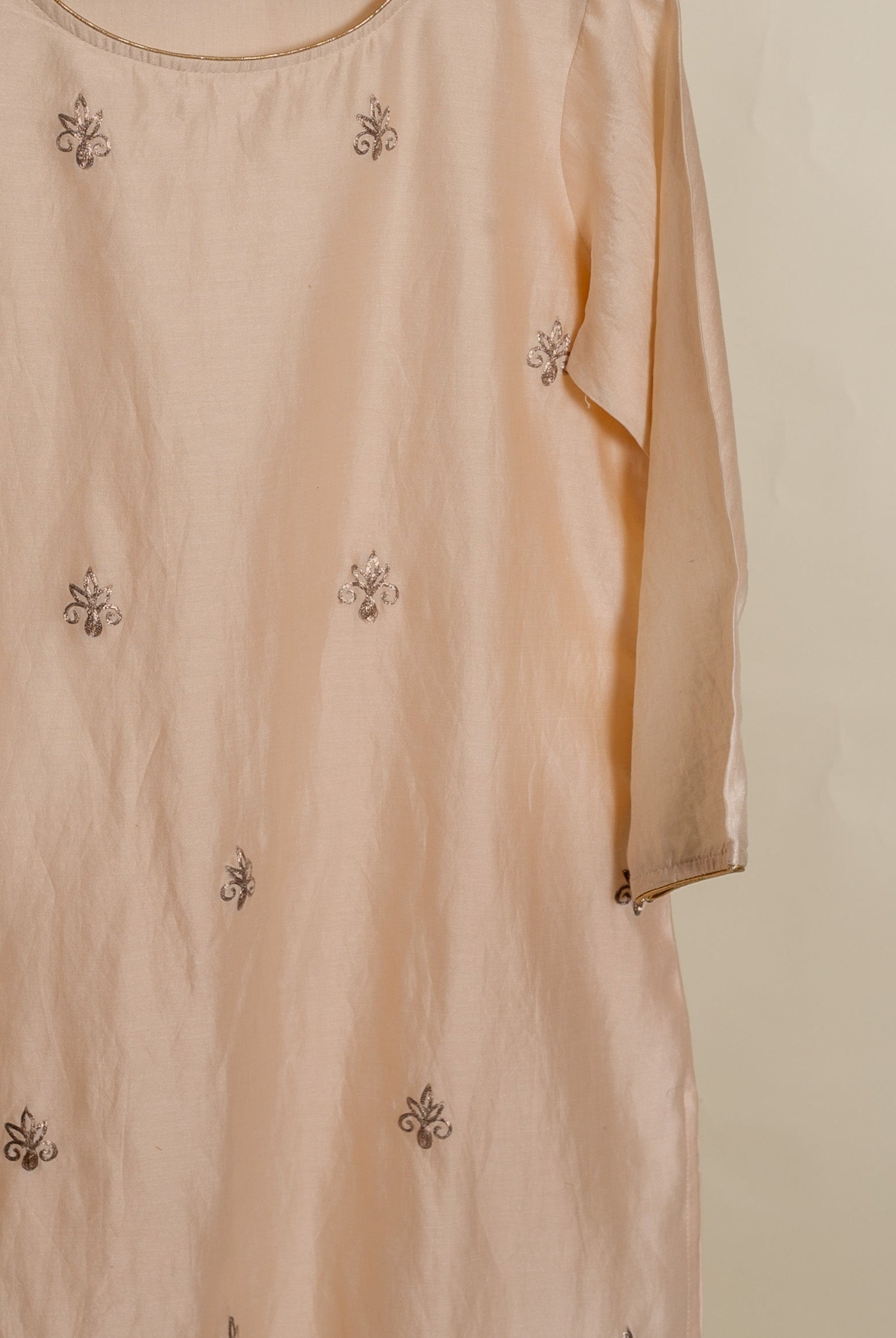A peach silk kurta with a round neckline and gold embroidery.