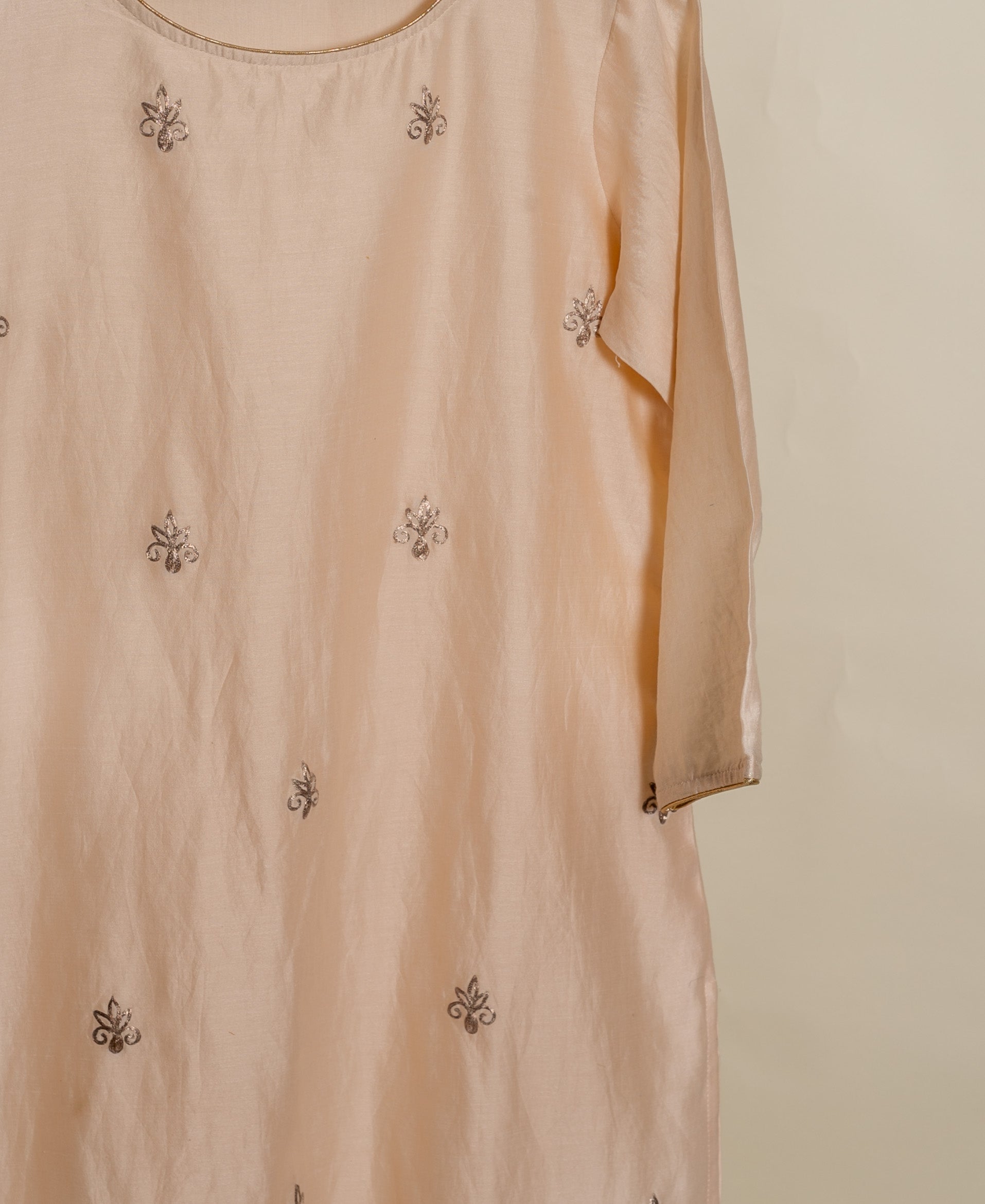 A peach silk kurta with a round neckline and gold embroidery.