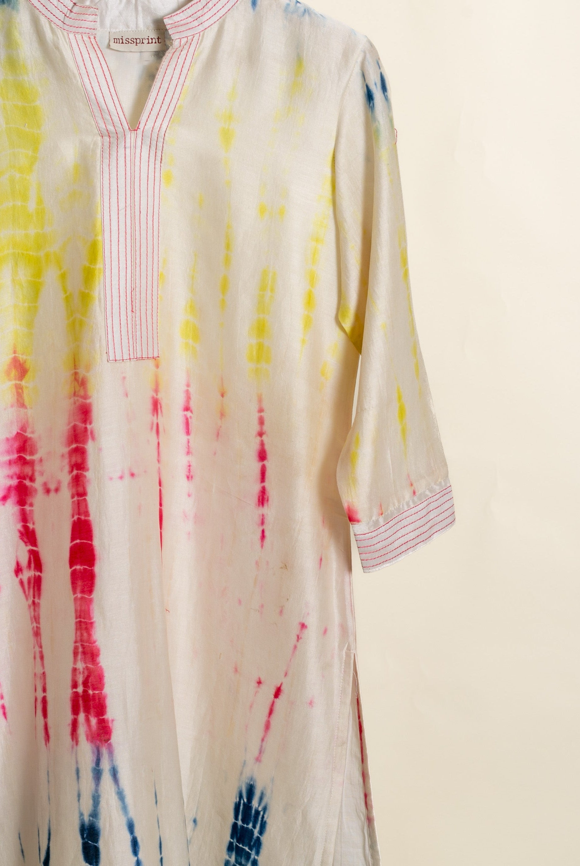 A white tie-dye kurta with pink and yellow accents.