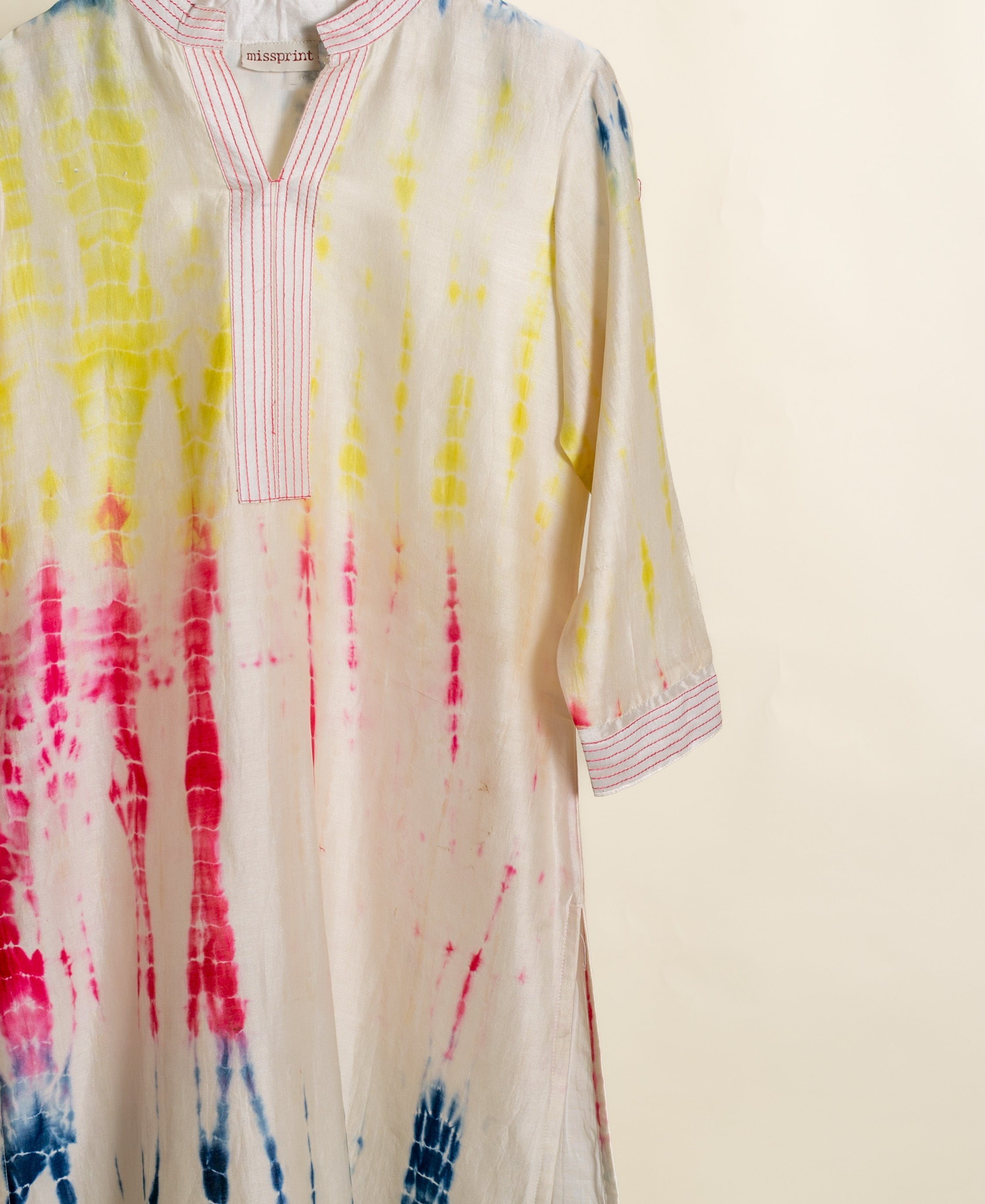 A white tie-dye kurta with pink and yellow accents.