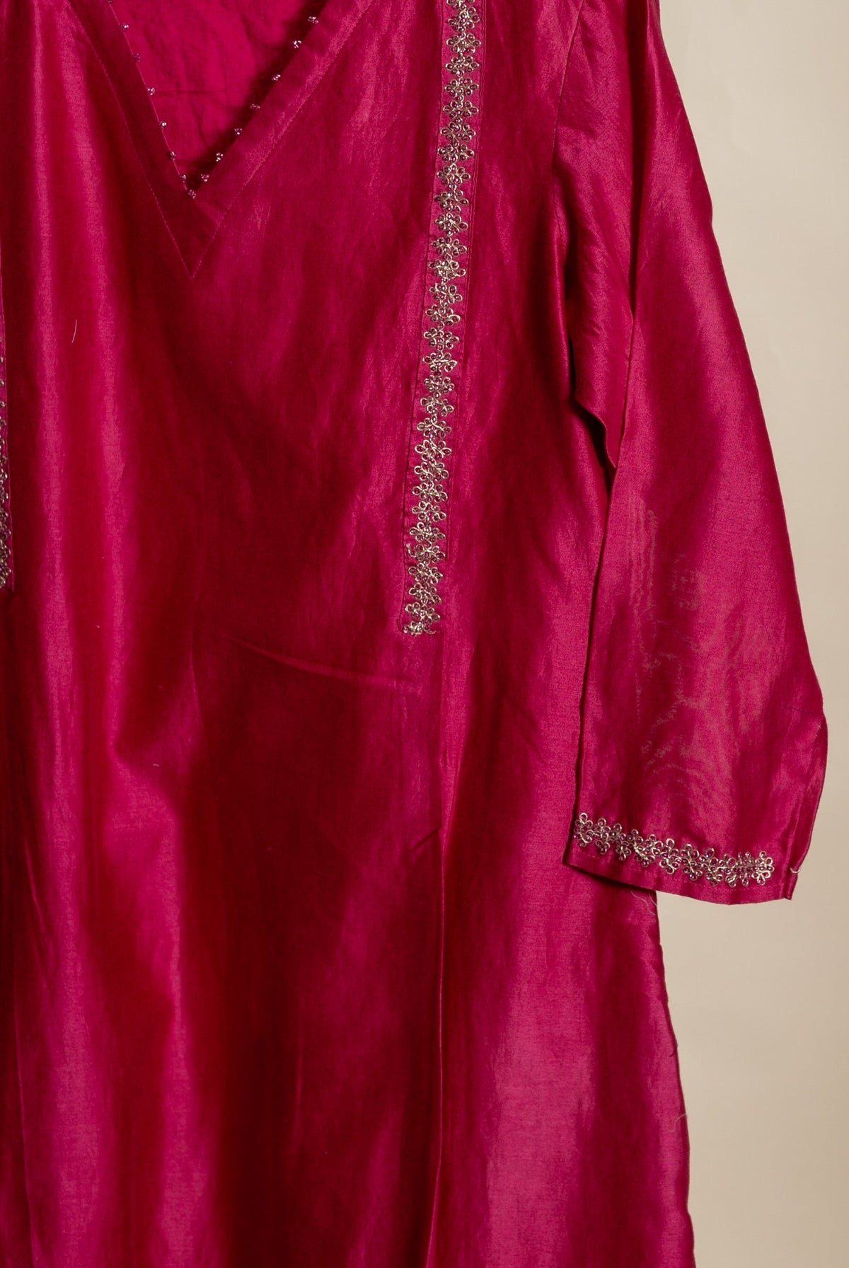 Hanging magenta Chanderi kurta with silver floral embroidery on V-neck, front, and sleeve cuffs.