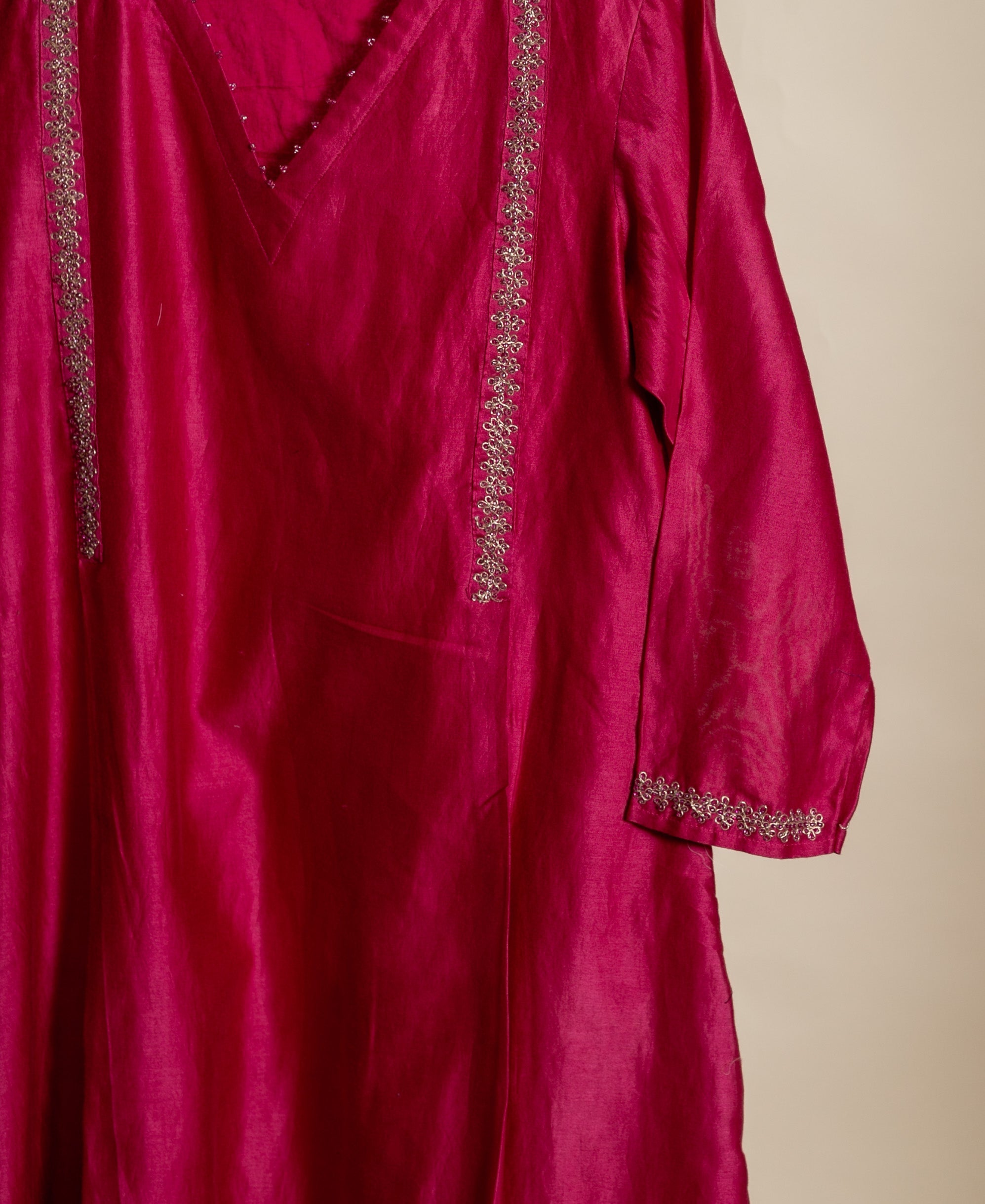 Hanging magenta Chanderi kurta with silver floral embroidery on V-neck, front, and sleeve cuffs.