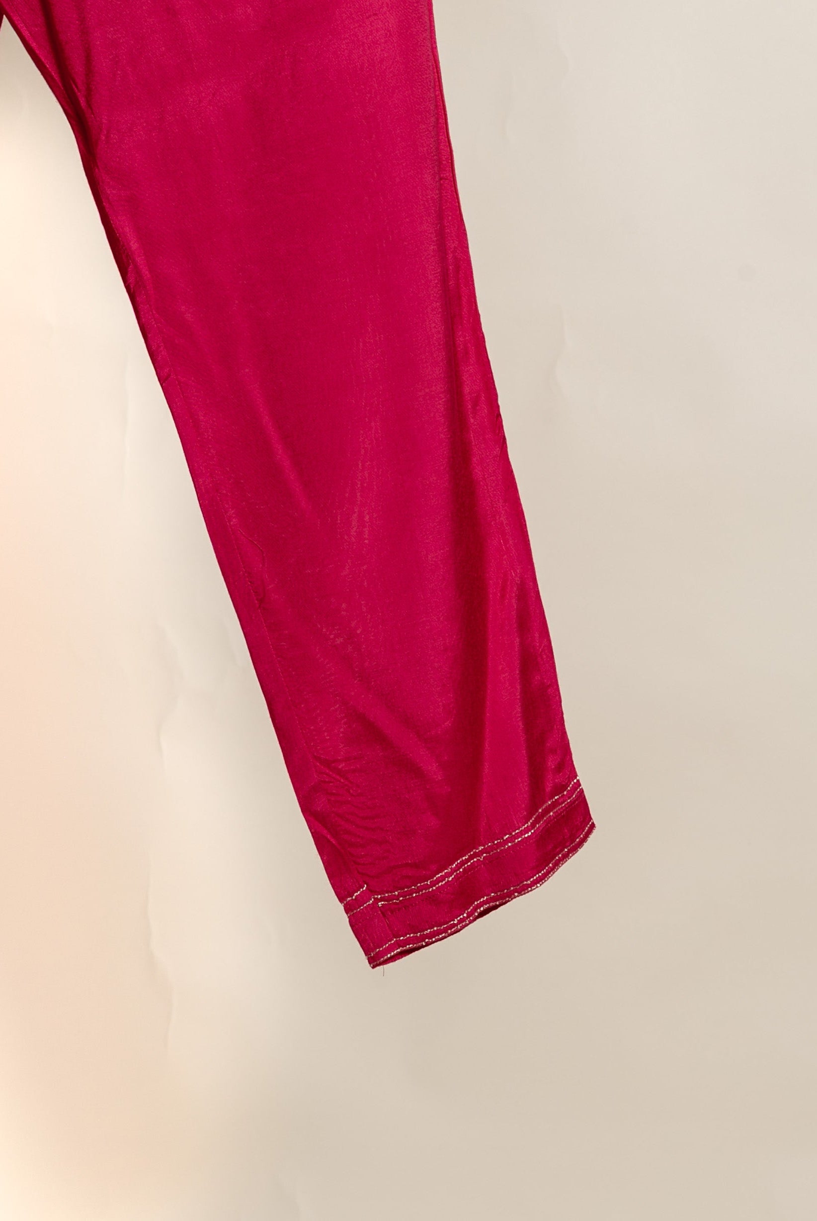 Vibrant magenta silk pants, partial view, with delicate silver double-stitched hem.